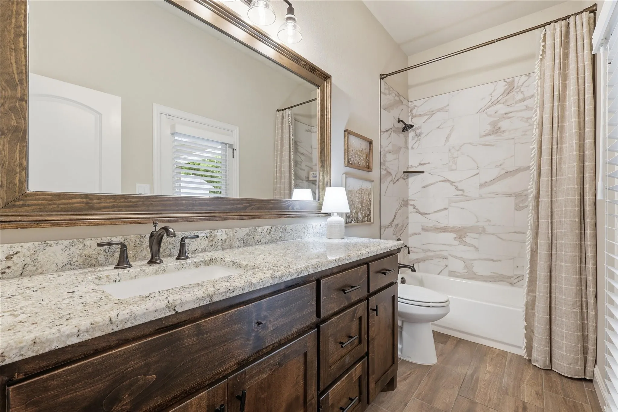 Bathroom vanity featuring a light-toned granite countertop with an undermount sink and a dark wood-finish cabinet