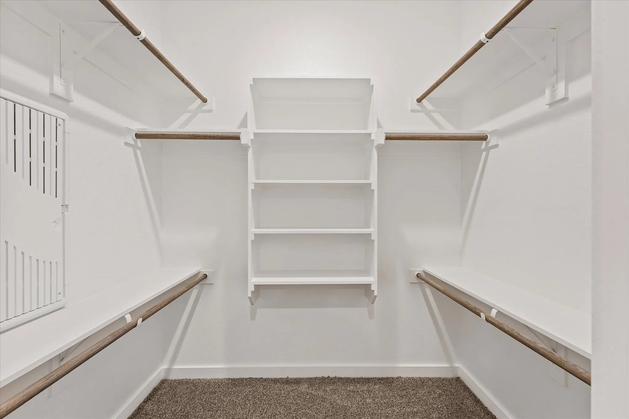 Walk-in closet featuring built-in shelving, multiple hanging rods, white walls, white trim, and carpet flooring
