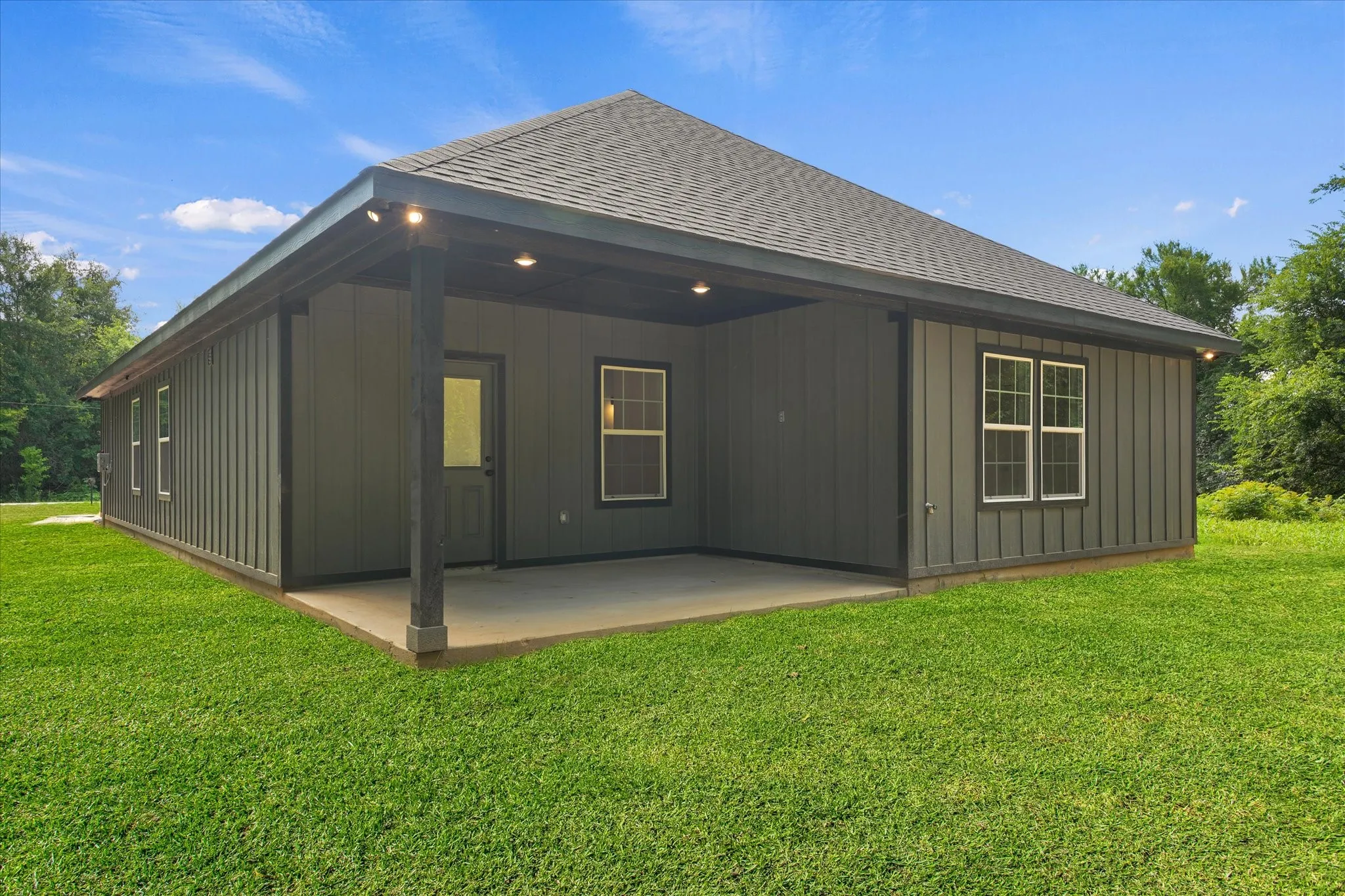 Covered patio with recessed lighting, board and batten siding, exterior door with glass insert, double-pane windows, and shingle roofing