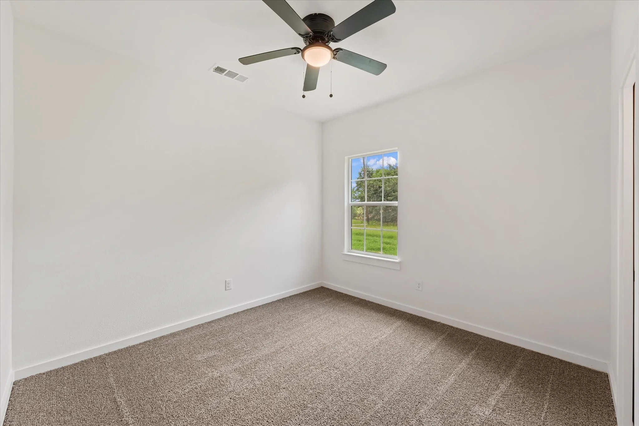 Carpeted interior room featuring a ceiling fan with integrated lighting, a single window, white walls, and white trim