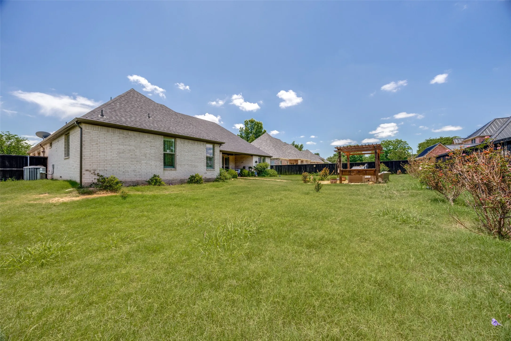 Fenced backyard with pergola and stone pathway to the patio