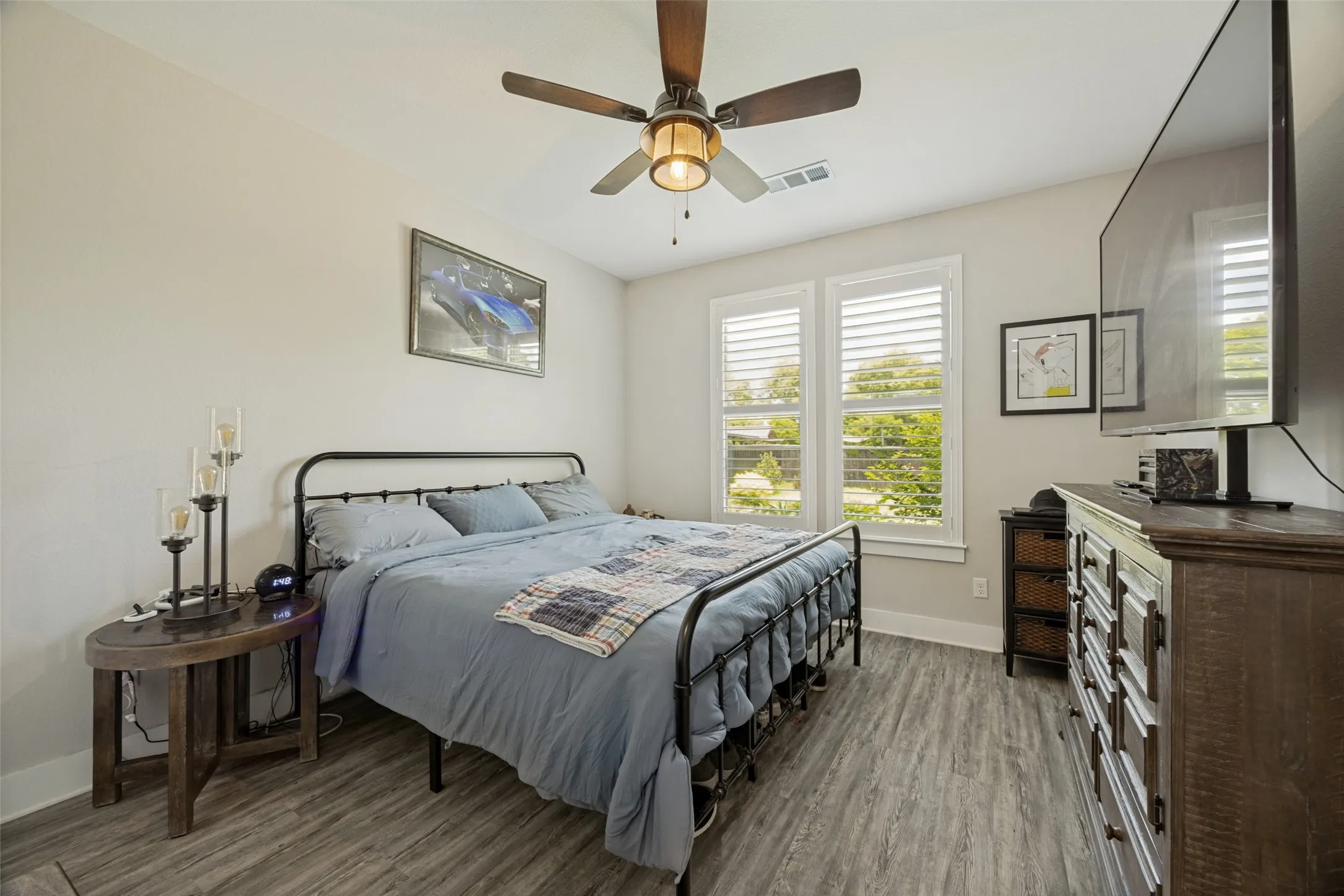 Room featuring wood-finish flooring, two large windows with blinds, and a ceiling fan with integrated lighting