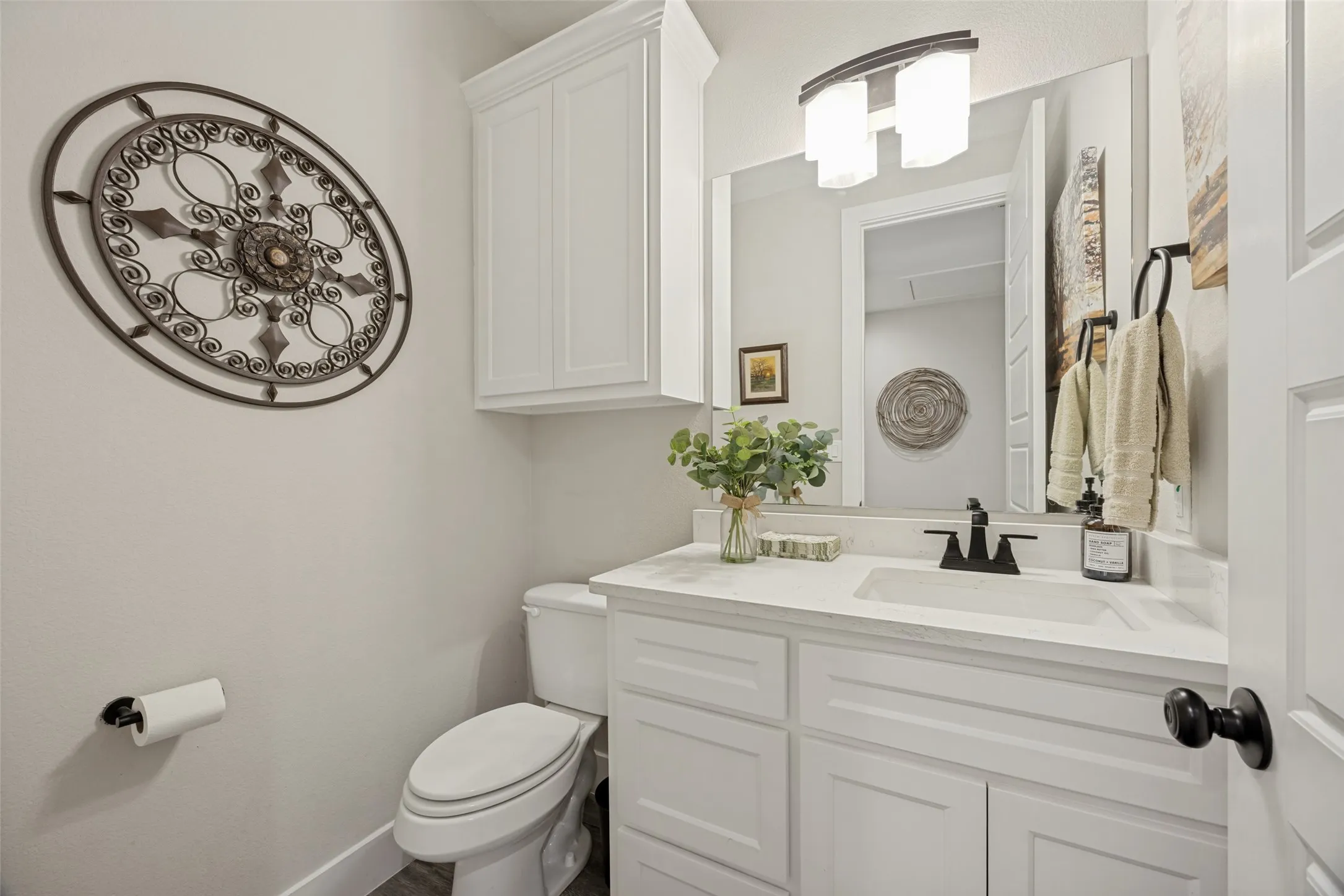Hallway Half Bathroom featuring a white vanity with built-in cabinetry, an undermount sink, a matte black faucet, and a large mirror