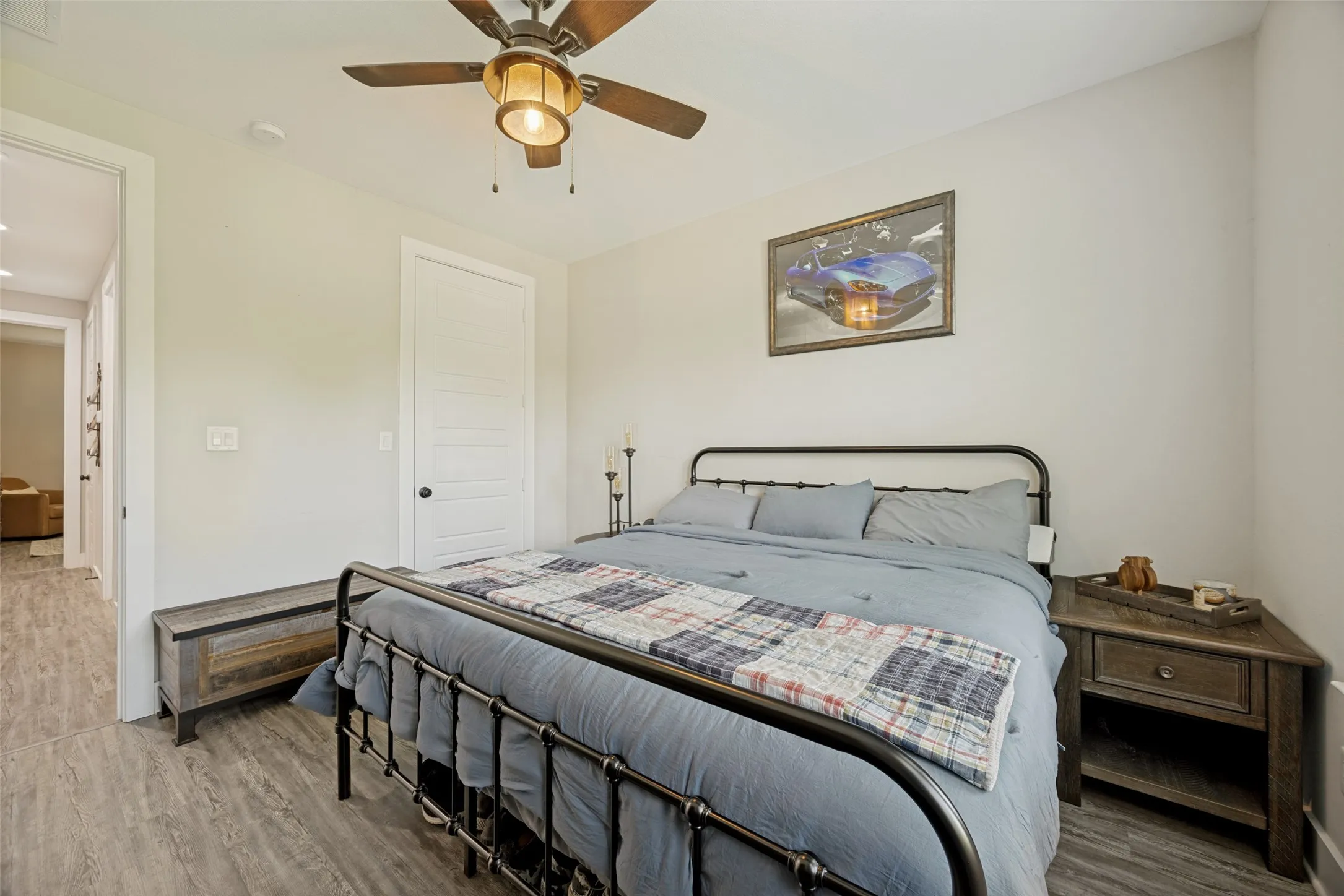 Spacious bedroom featuring light-toned walls and wood-finish flooring