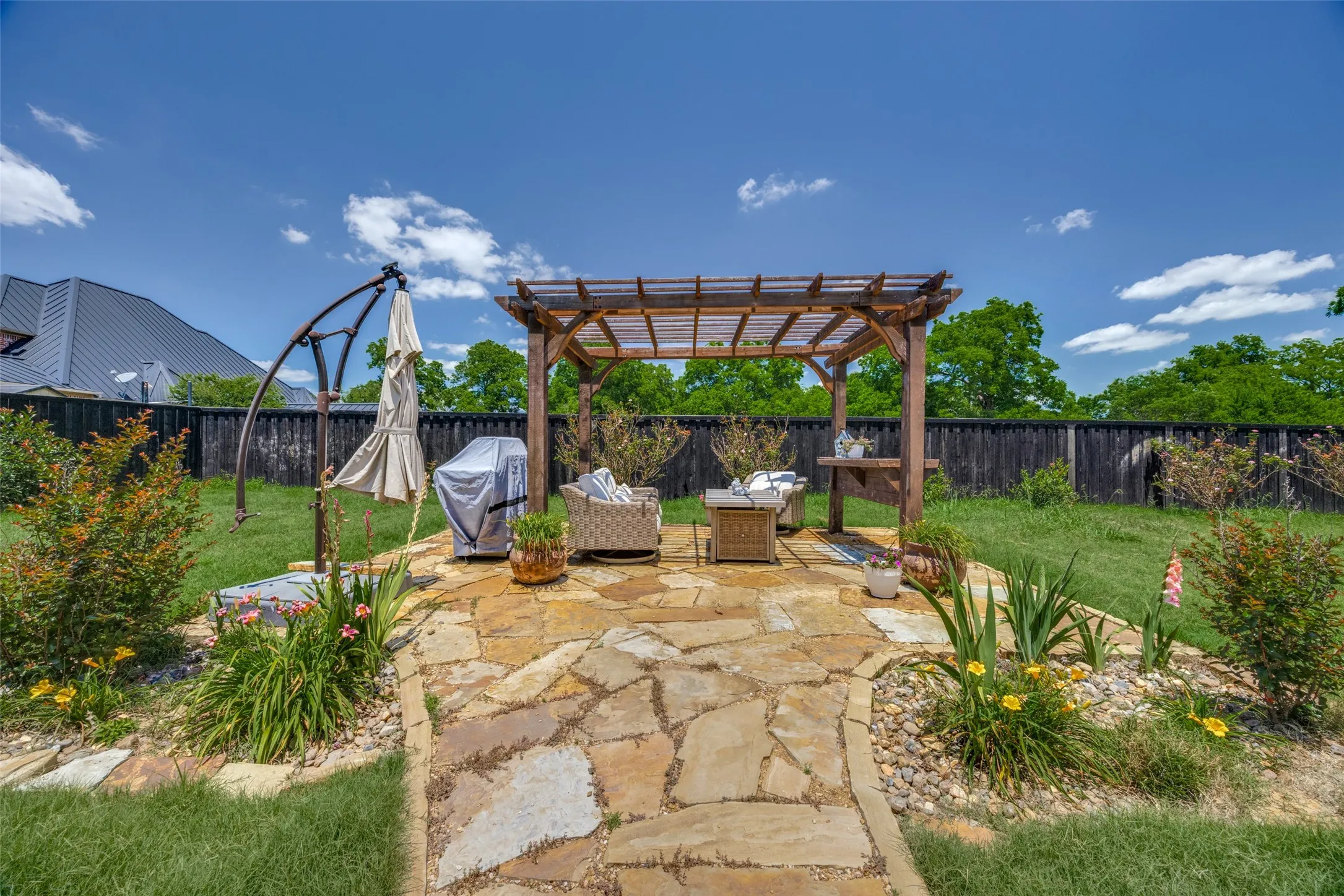 Expanded area of the patio, featuring a pergola and stone pathway with some lovely landscaping.
