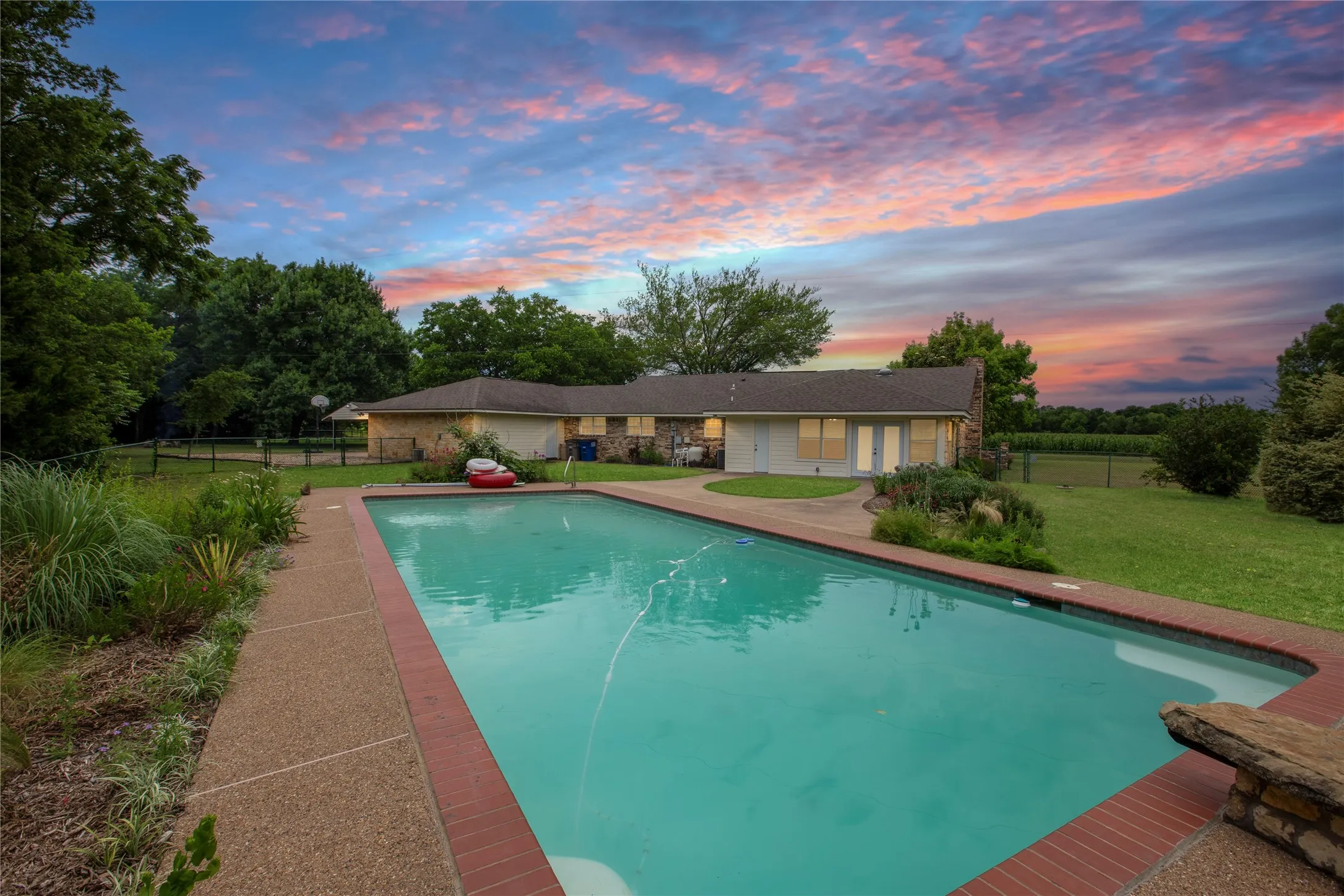 Pool View From Back Corner Across Towards the House. Pool Features Include Diving Rock, Step Entry wHand Rail & Corner Swim Seats.