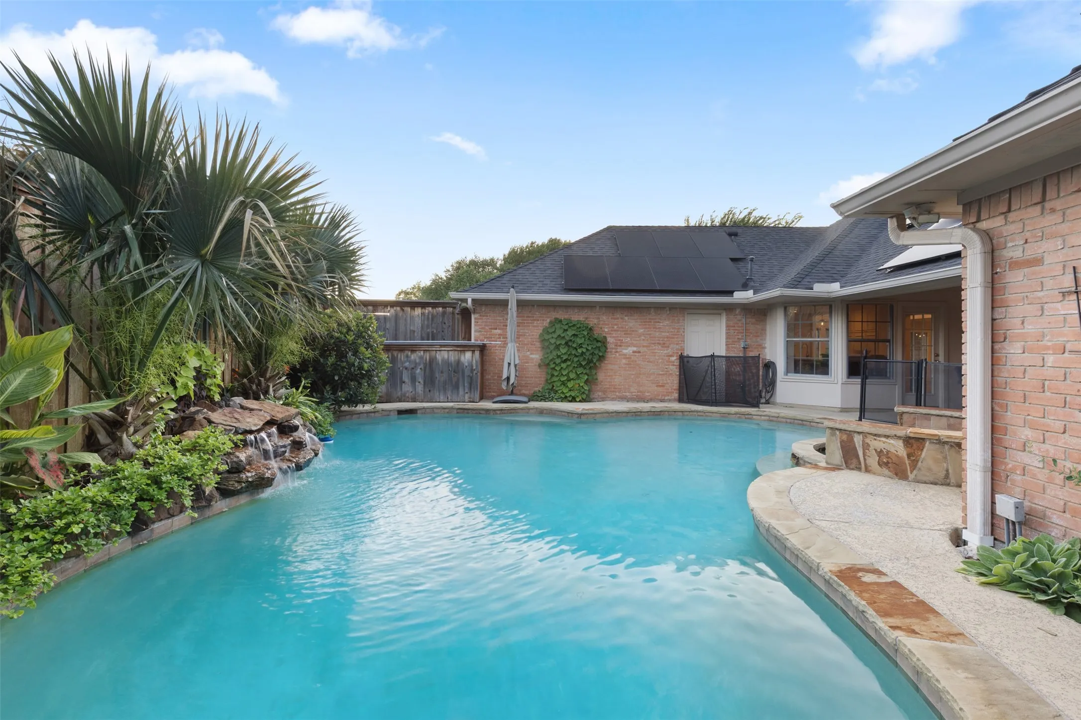 View from side-yard with water feature, landscape and back porch.