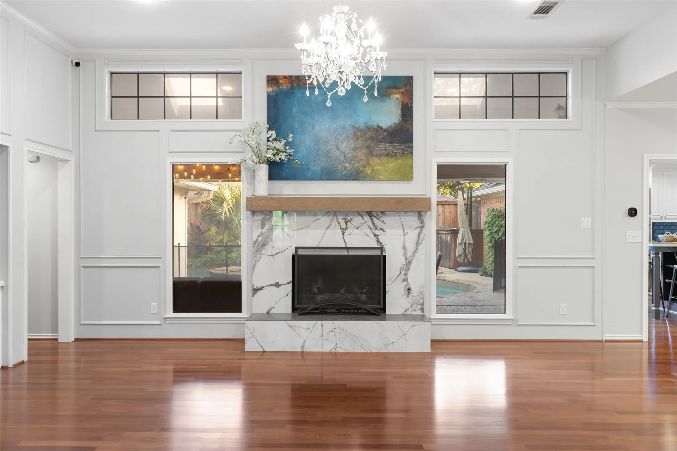 Spacious living area with chandelier and large fireplace.