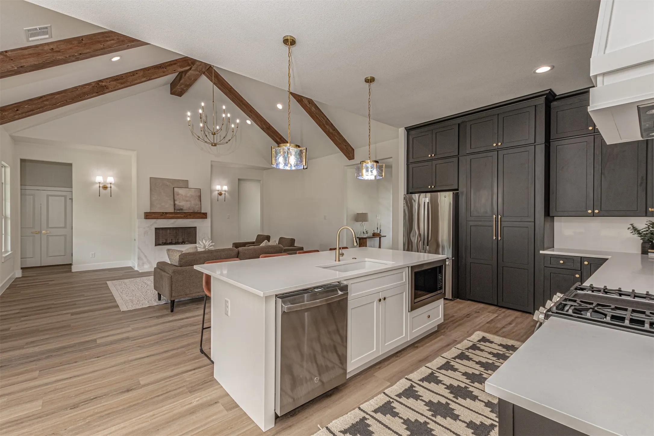 Open-concept kitchen and living area featuring vaulted ceilings with exposed wood beams