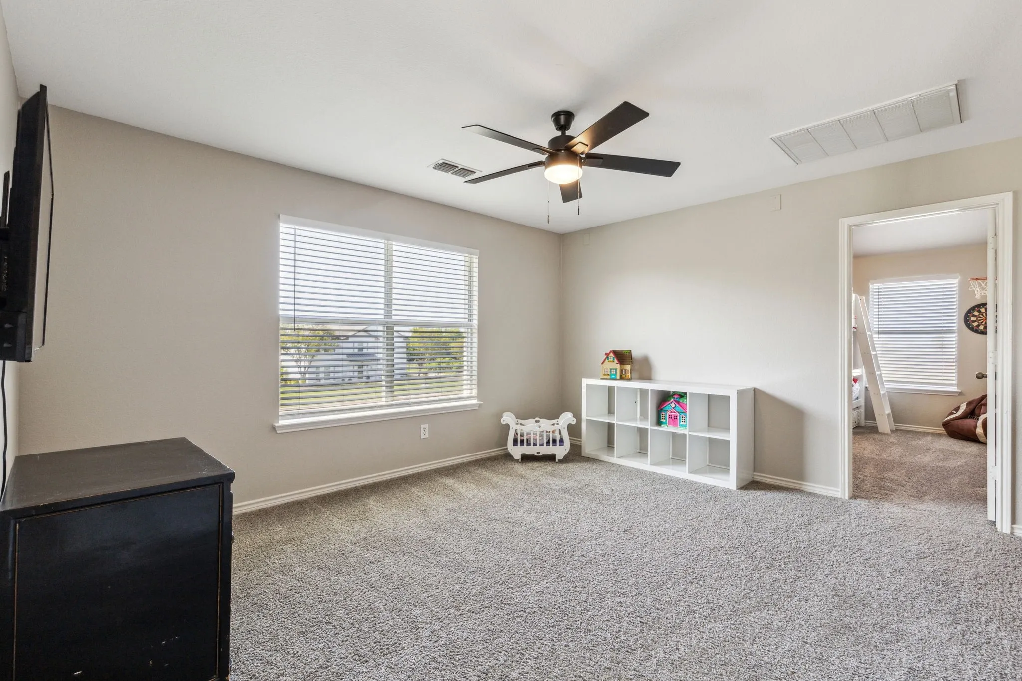large upstairs game room with natural light and ceiling fan.
