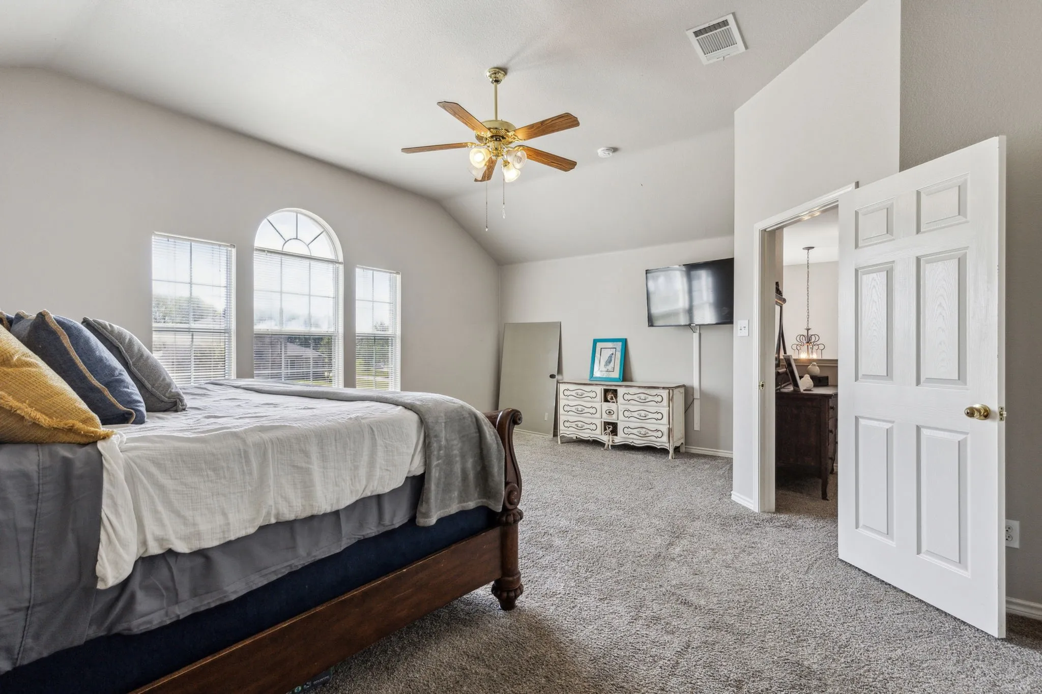 Another view of the primary suite witth beautiful natural light, carpet and ceiling fan.