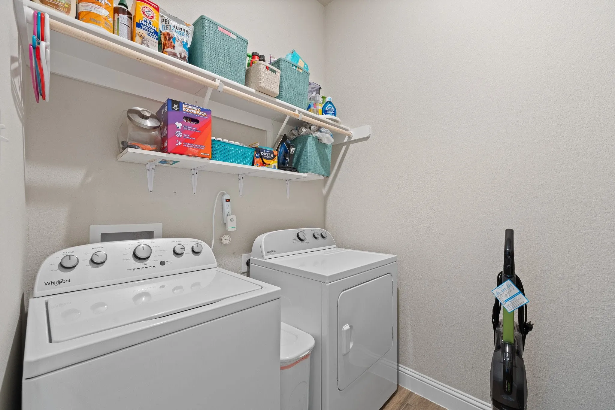 Dedicated laundry area featuring a washer and dryer, wood-finish flooring, and two levels of built-in shelving