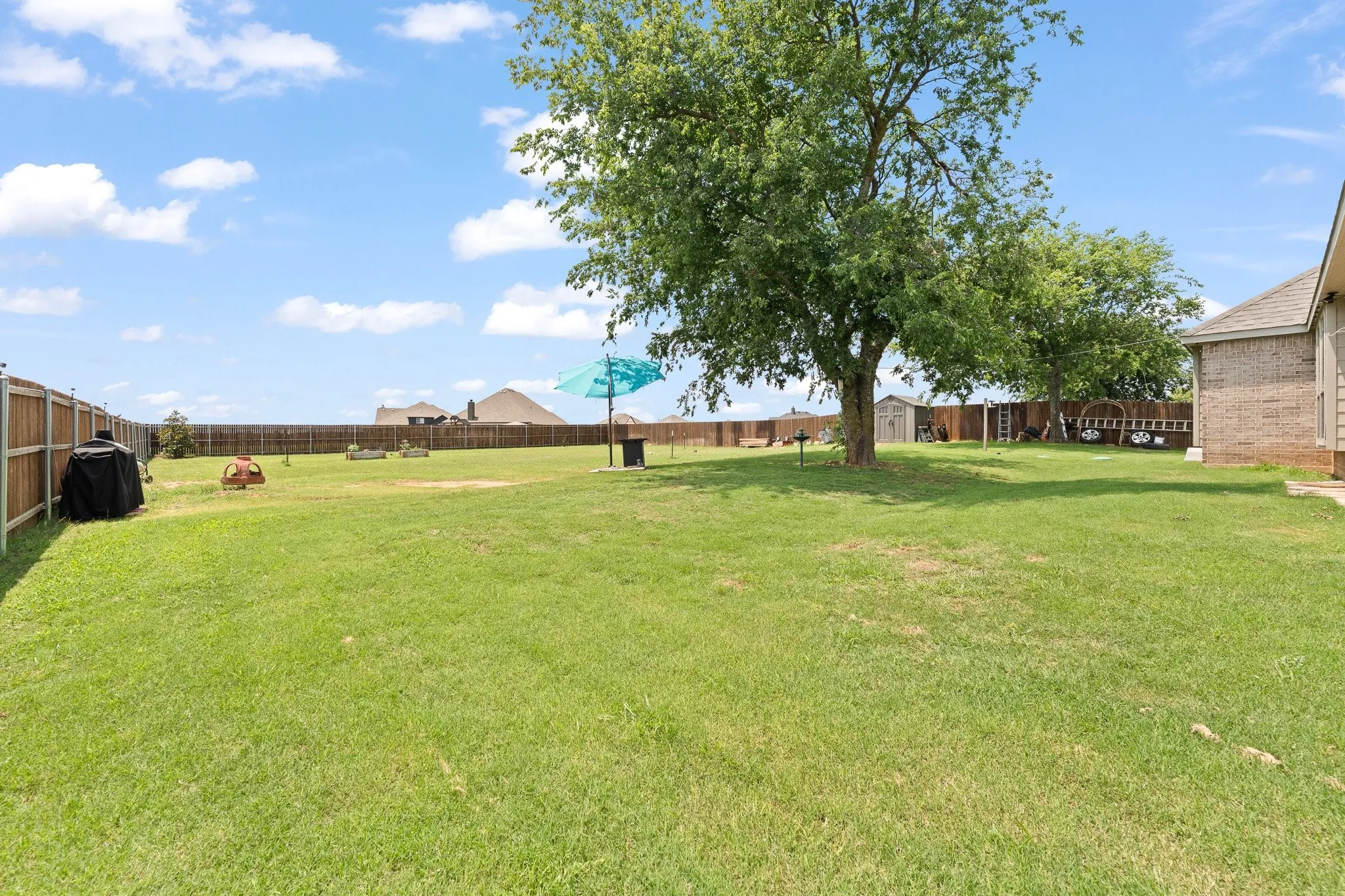 Expansive green lawn with mature trees and a wood privacy fence