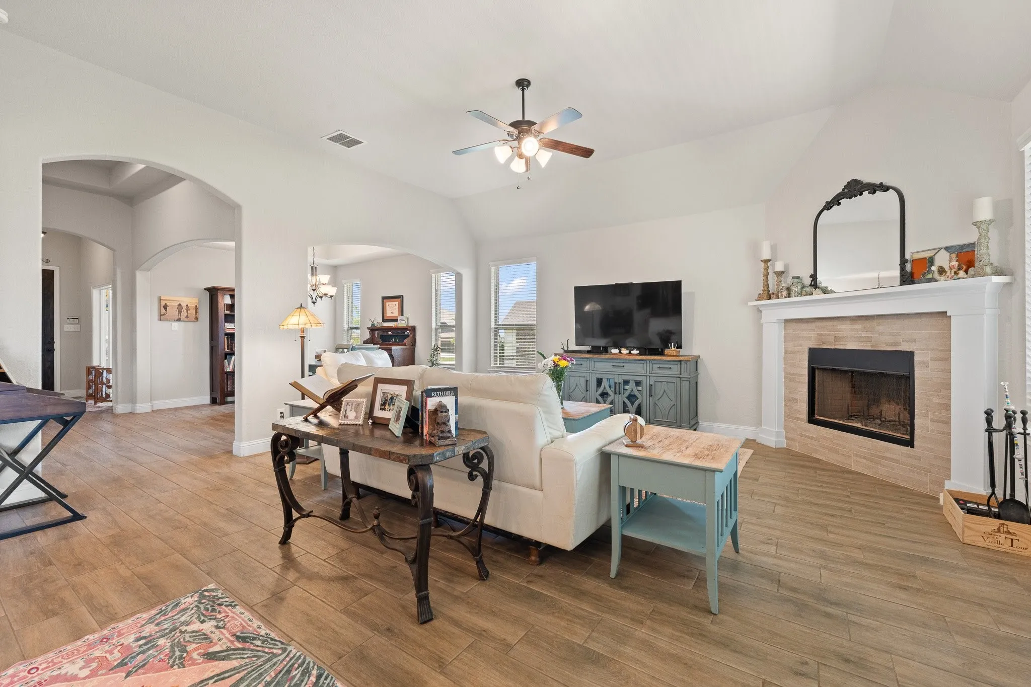 Bright living space featuring wood-finish flooring, a ceiling fan, and arched doorways