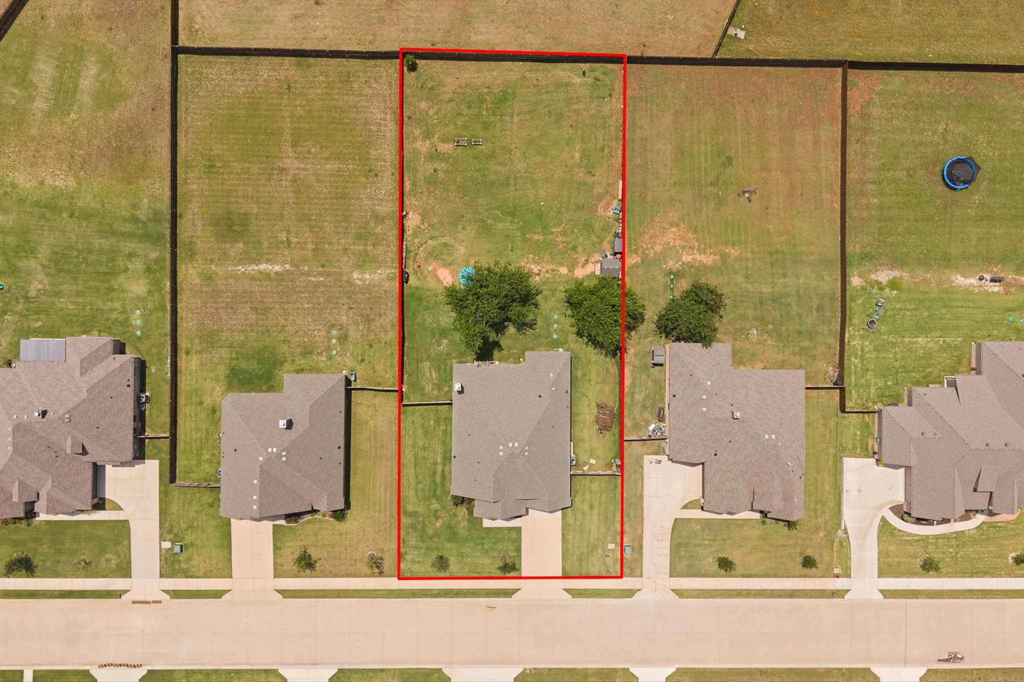 Aerial view of a residential property outlined in red, featuring a single-family home with a brown shingle roof