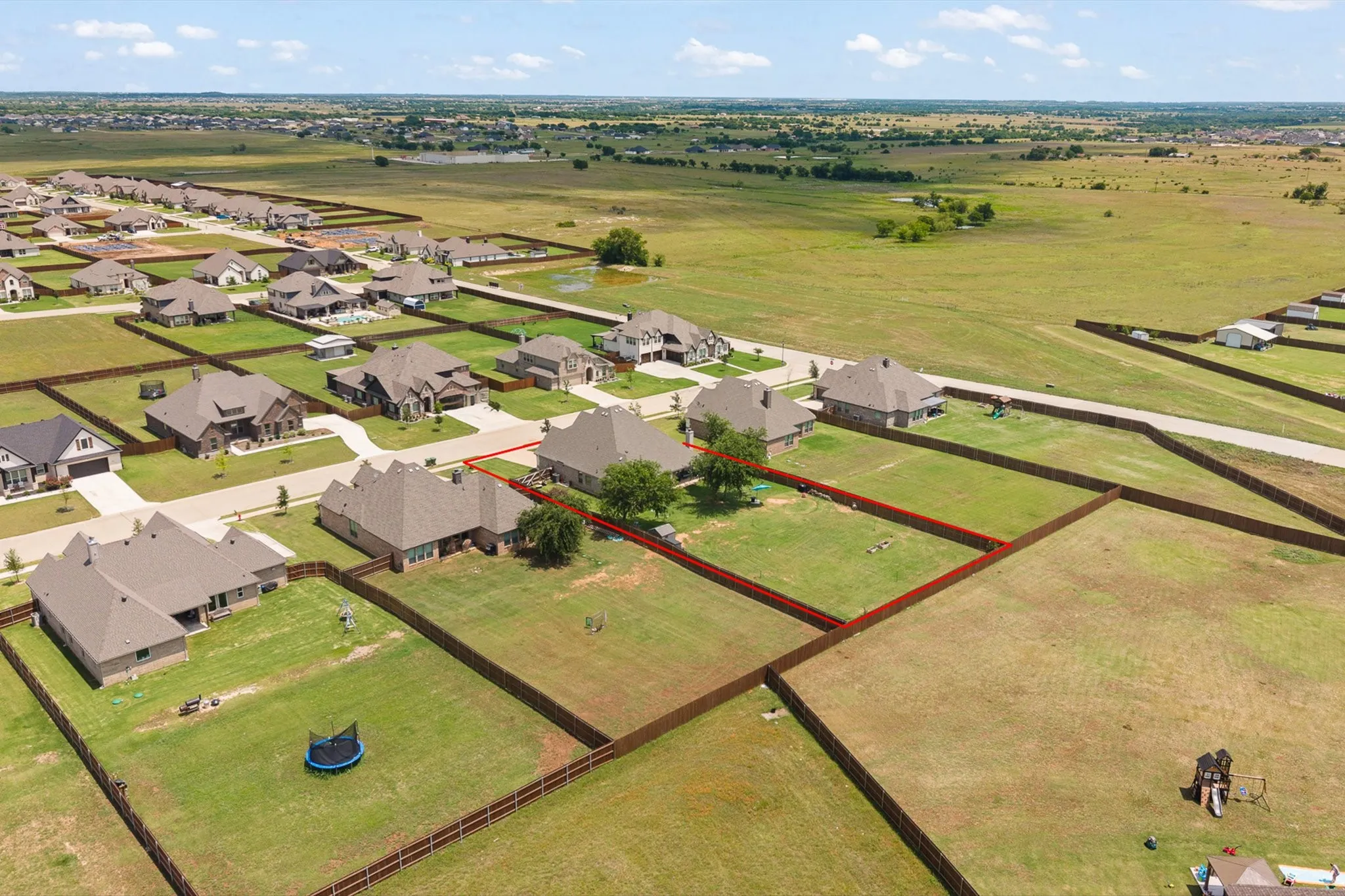 Expansive lot with defined boundaries and a partial privacy fence, bordering a residential street