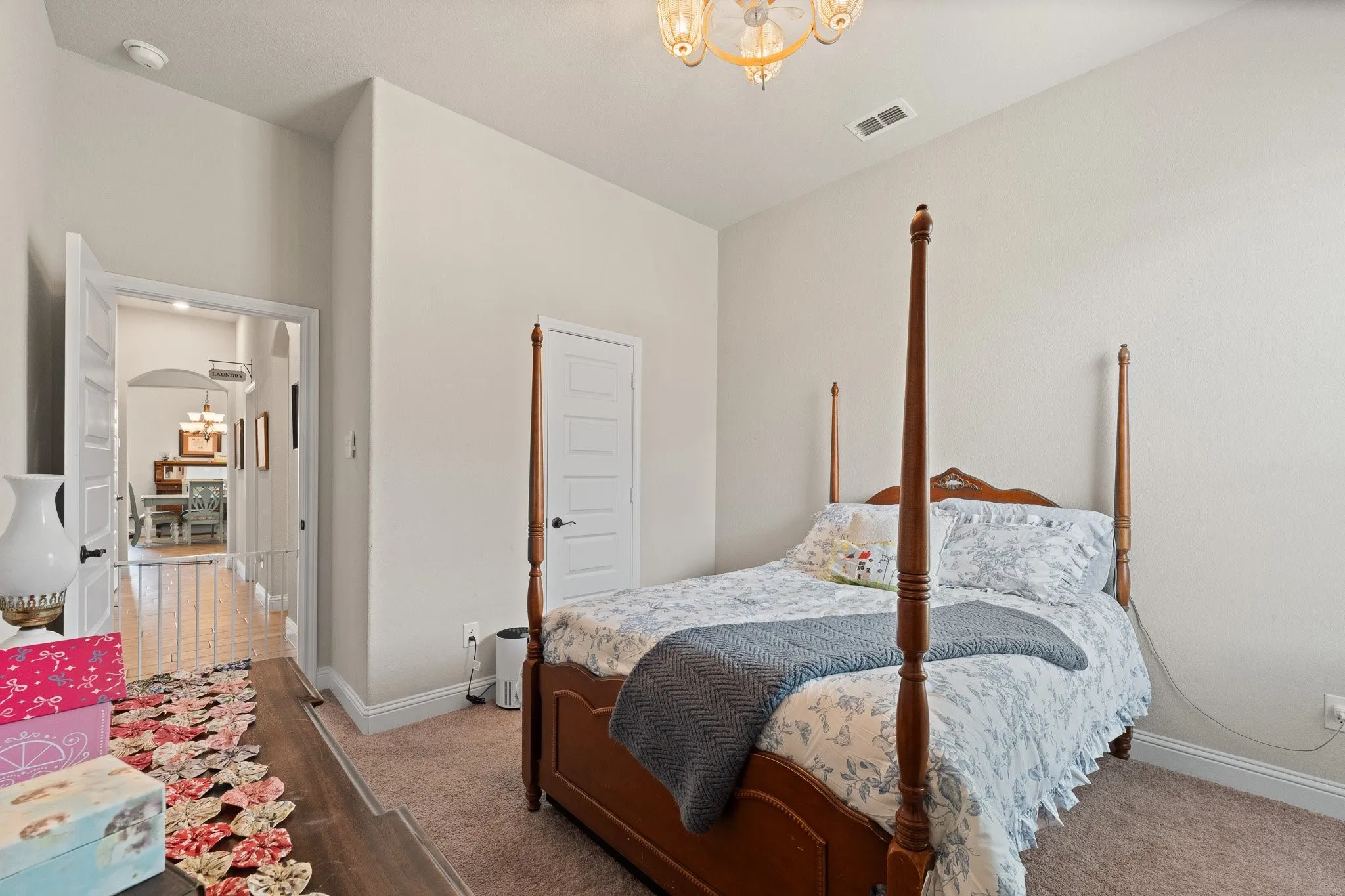 Carpeted room with light neutral wall tones, a five-panel interior door, and an ornate ceiling light fixture