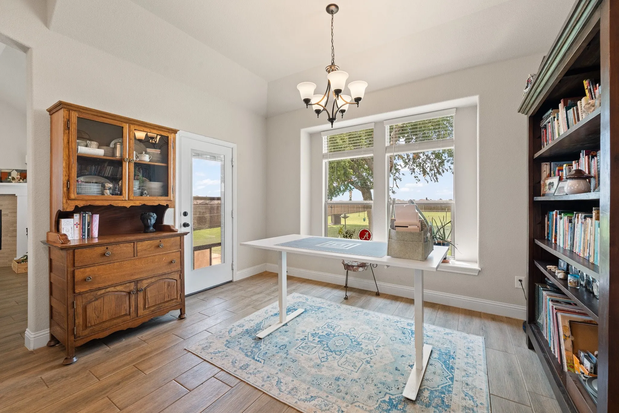 Room featuring wood-finish tile flooring, a large window with blinds, and a glass-paneled exterior door