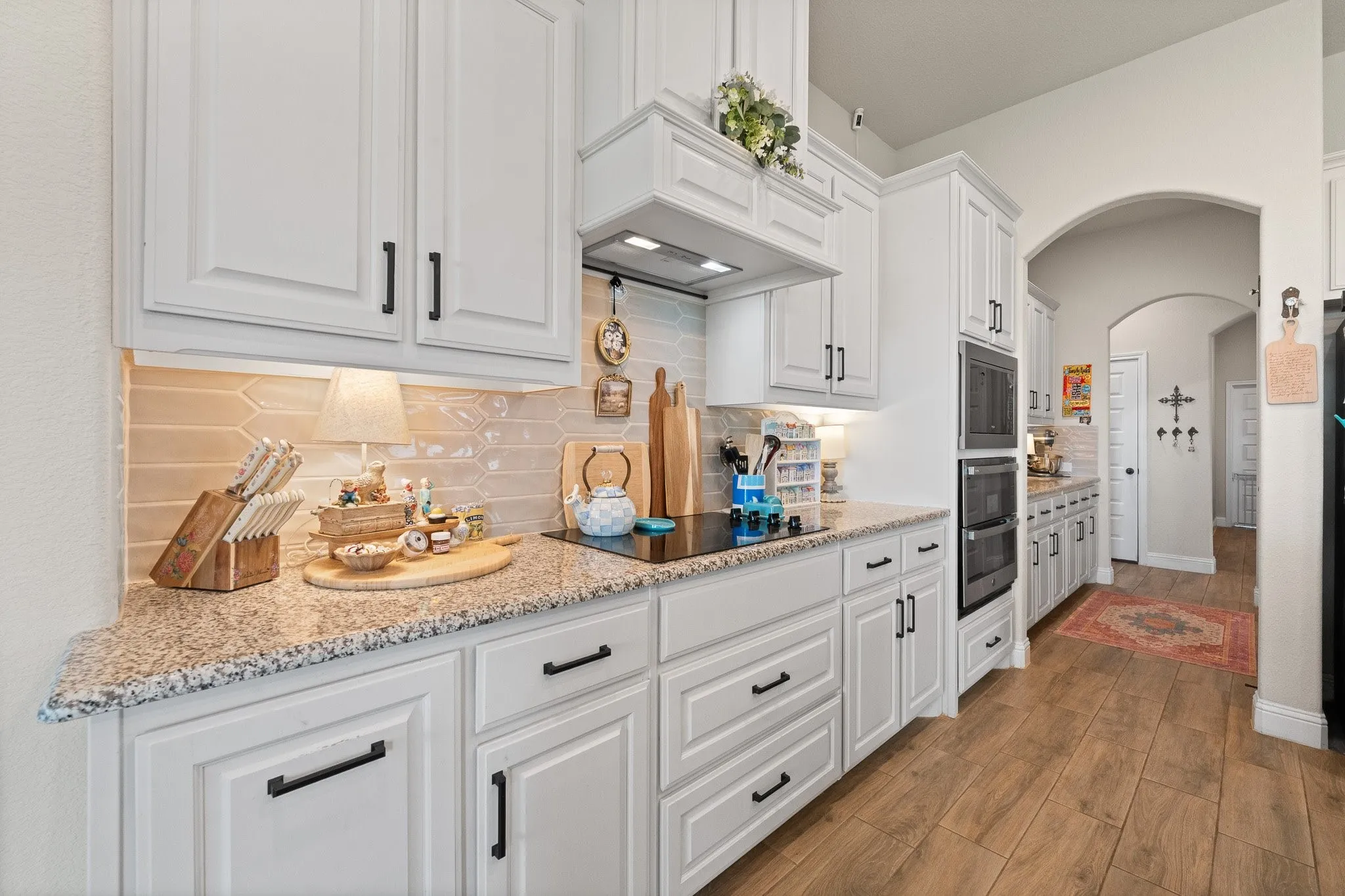 Kitchen featuring white cabinetry with dark hardware, speckled countertops, and a subway tile backsplash