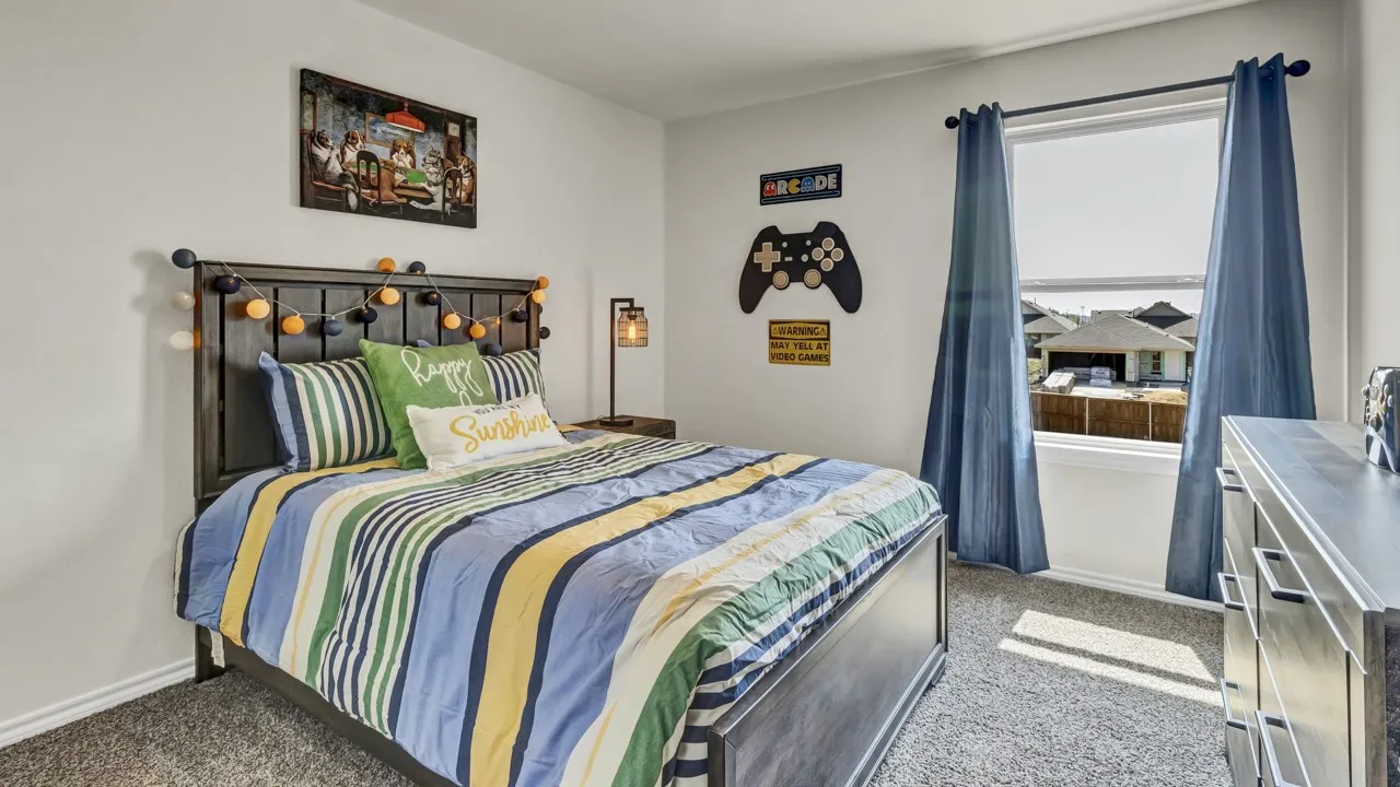 Carpeted room featuring a window with roller shades and blue drapes, a dark wood headboard, and light gray walls