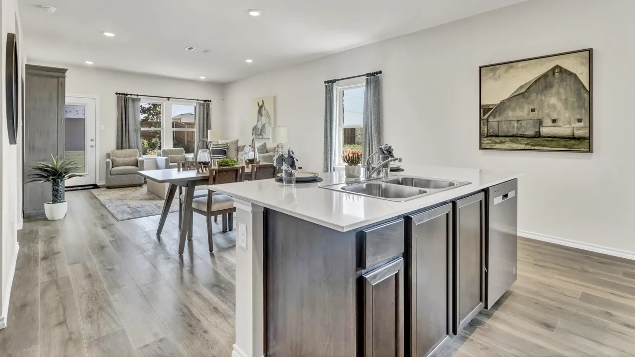 Open-concept living space featuring wood-finish flooring, recessed lighting, and a kitchen island with dual sinks and stainless steel appliances