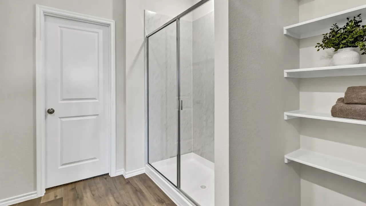 Walk-in shower with clear glass enclosure and tile surround