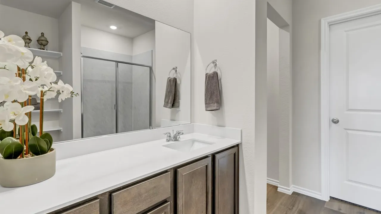 Bathroom featuring a single vanity with a white countertop, dark wood-finish cabinetry, and a large mirror