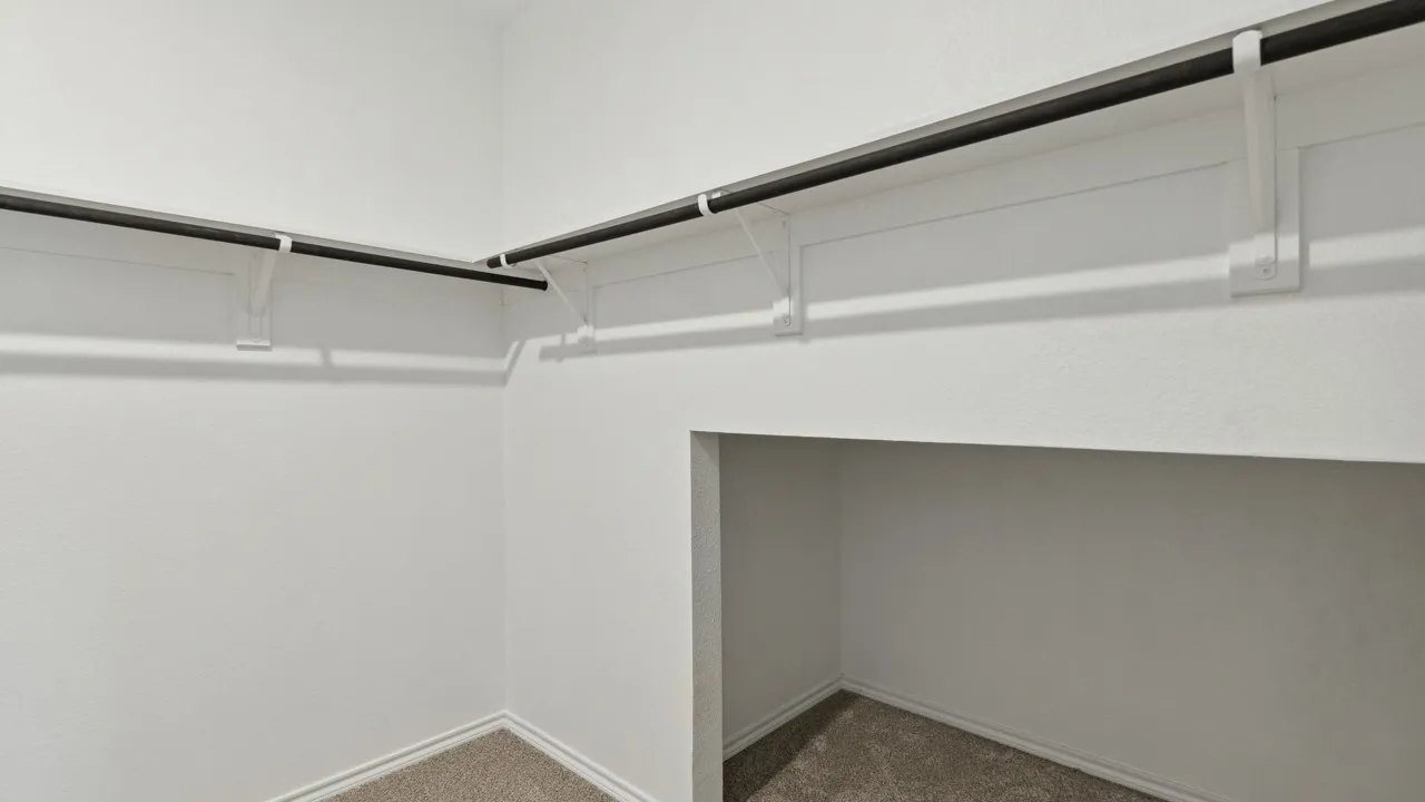 Walk-in closet featuring white walls, textured carpeting, and dual-level hanging rods