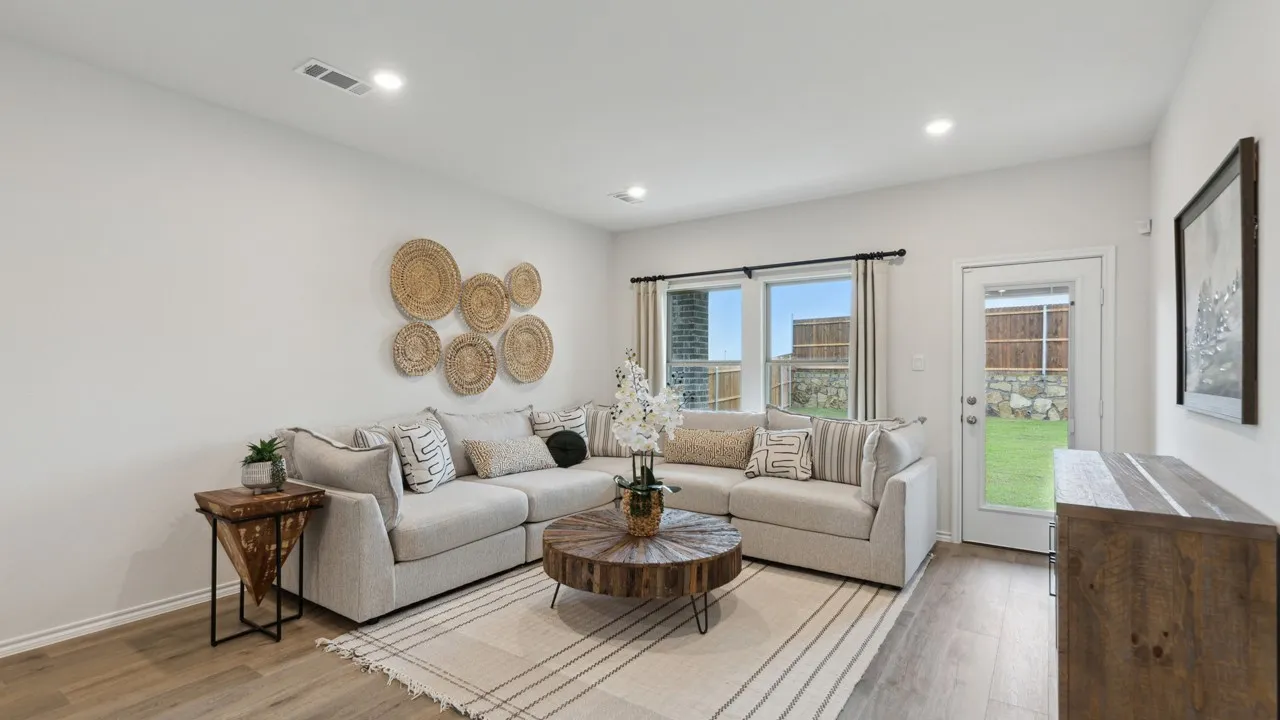 Open-concept living space featuring wood-finish flooring, recessed lighting, large windows with black trim, and a glass-paneled door leading to the exterior