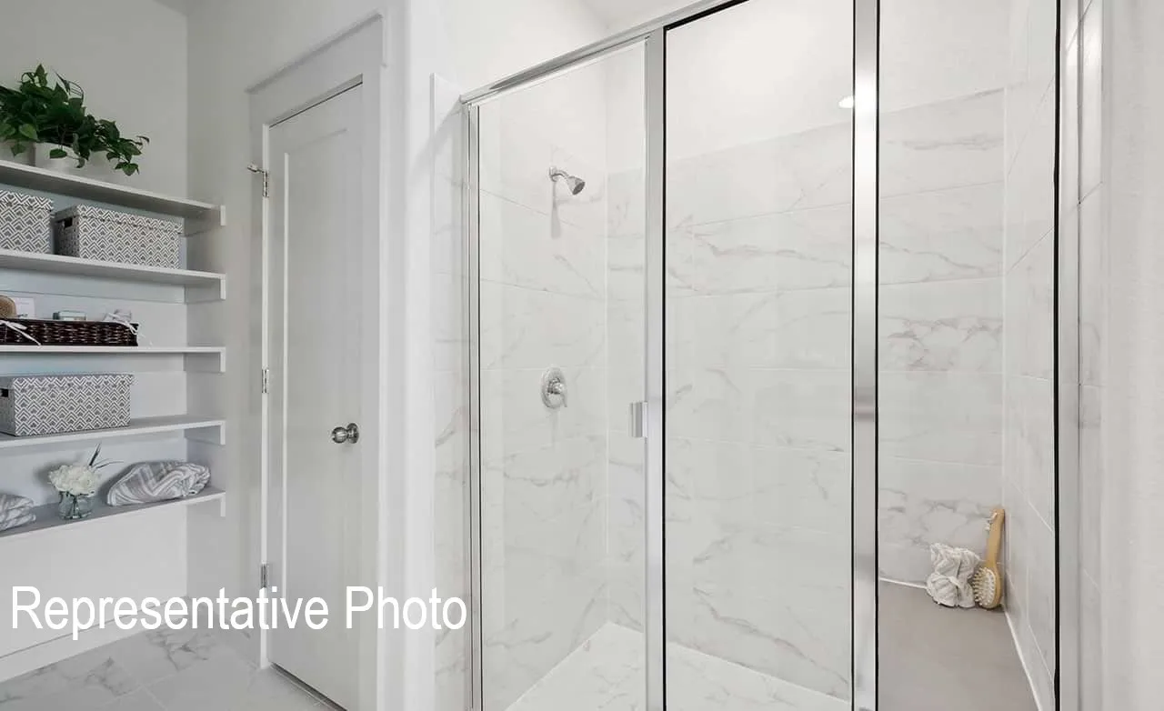 Walk-in shower with clear glass enclosure, white marble-look wall tiles, and a built-in shower niche