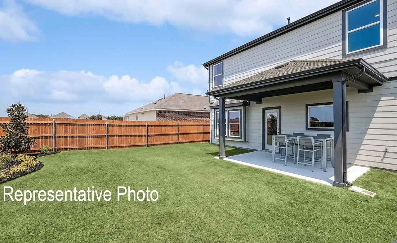 Spacious backyard featuring a manicured lawn, full privacy fencing, and a covered concrete patio