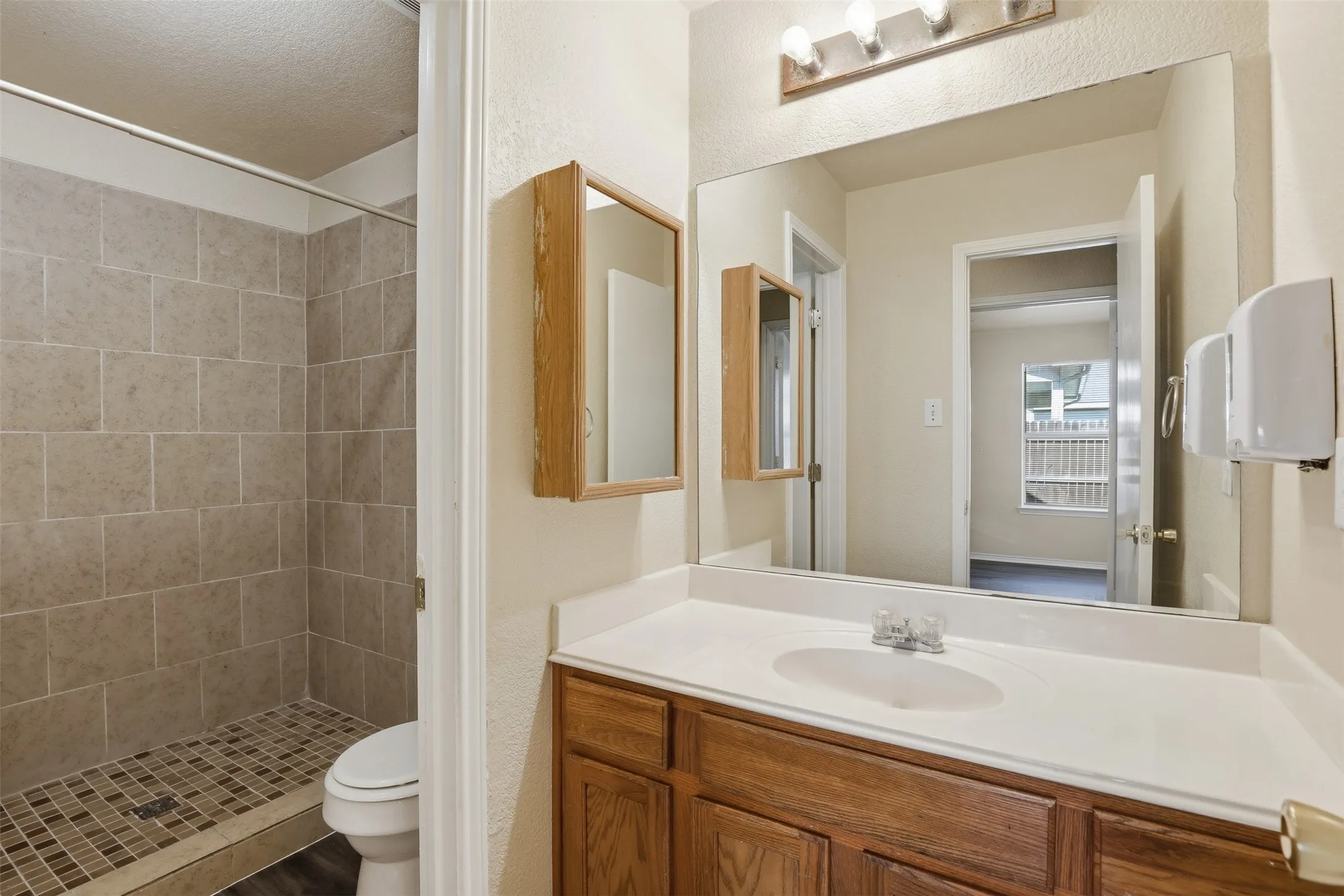Bathroom featuring a wood-finish vanity with a white countertop, an integrated sink, and a large wall-mounted mirror