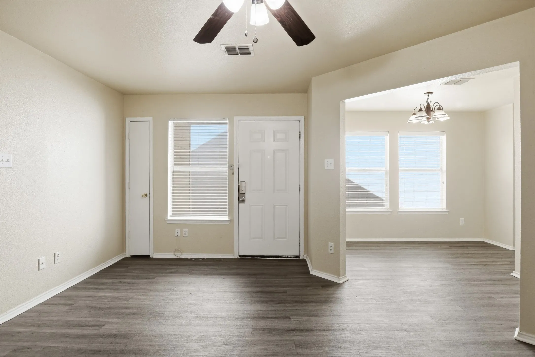 Foyer entrance featuring wood-finish flooring, a ceiling fan, and an arched doorway leading to an additional space with multiple windows and a chandelier
