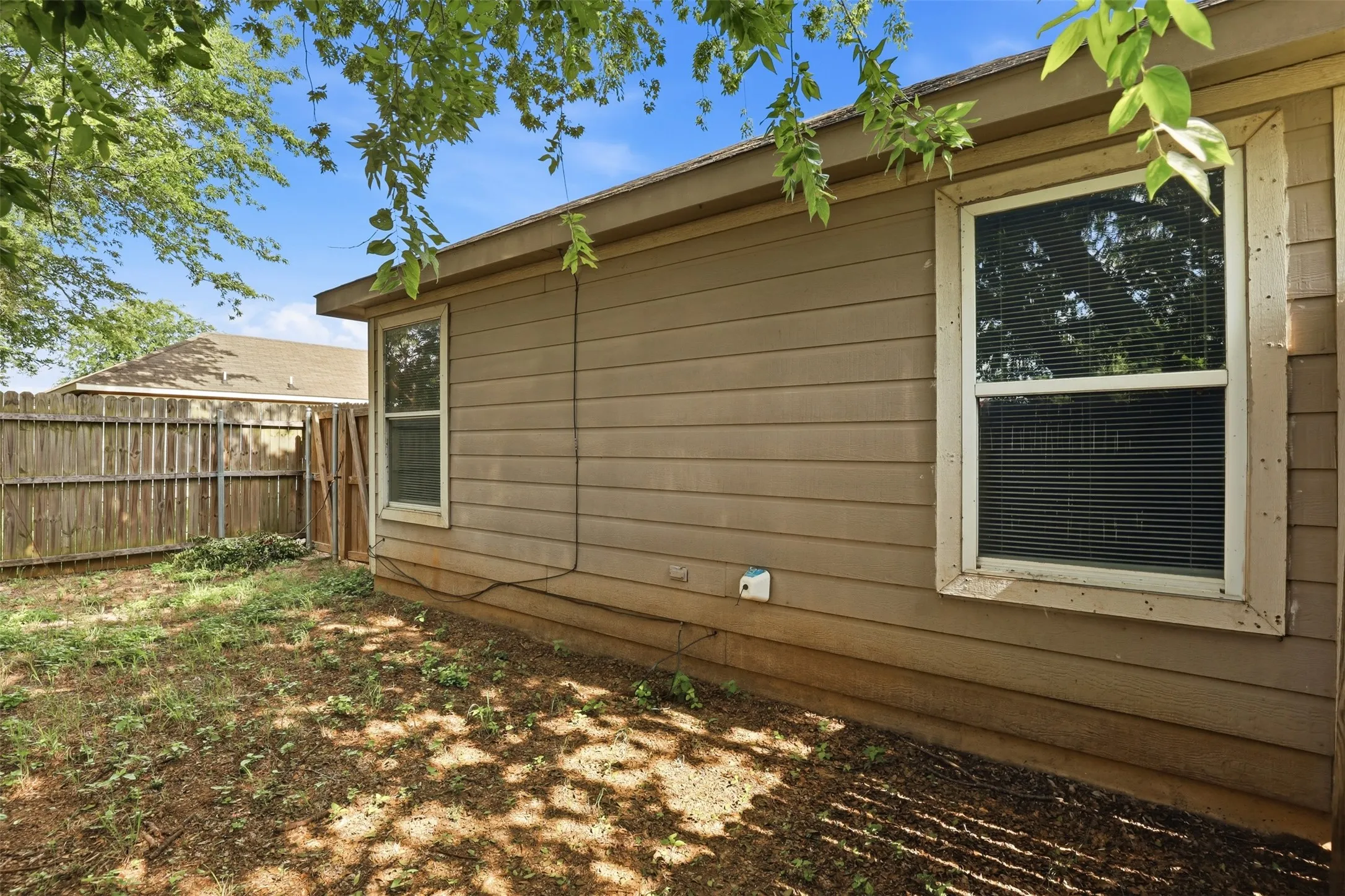 Tan siding exterior with two windows featuring blinds