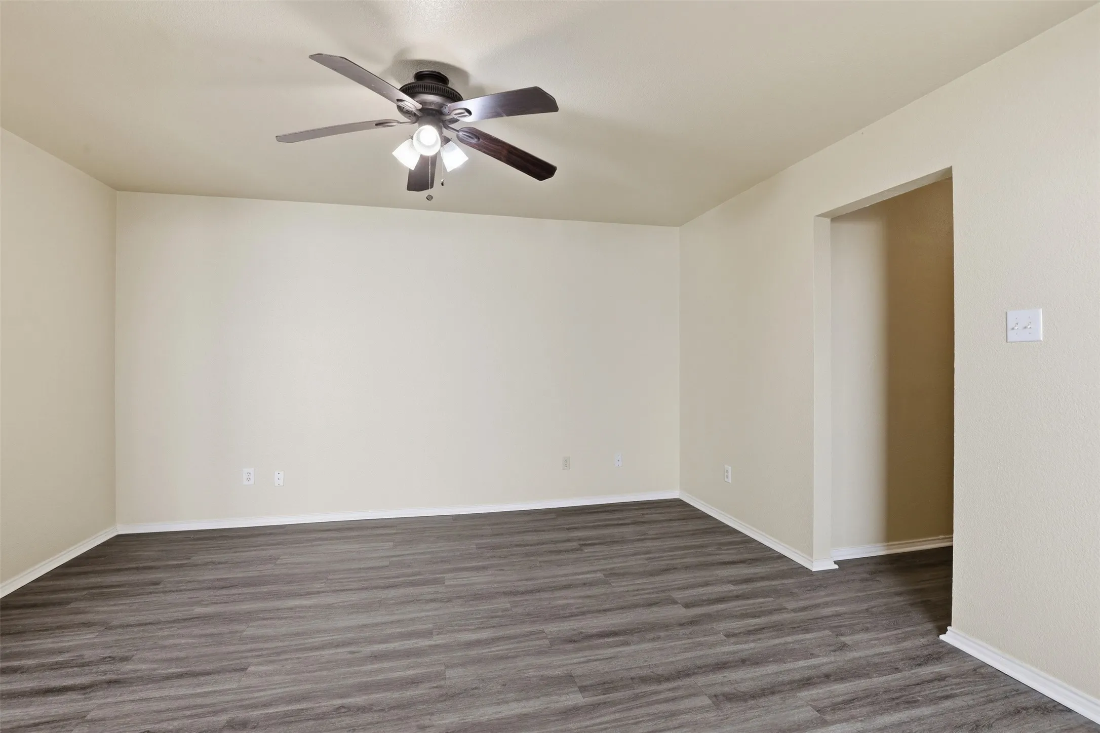 Open interior space featuring wood-finish flooring, light-toned walls, and white baseboards