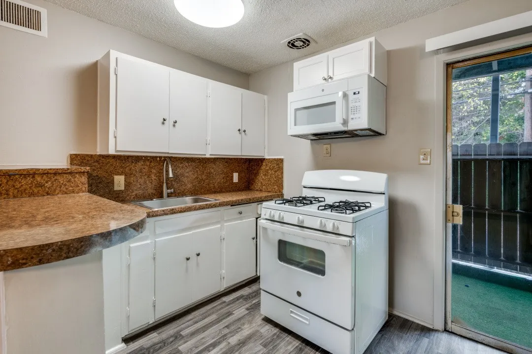 Compact kitchen featuring white cabinetry, a built-in microwave, and a gas range