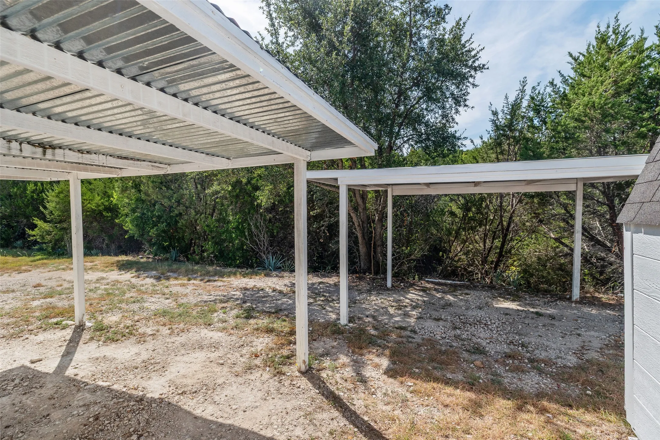 Dual carports with white painted metal frames and corrugated metal roofs