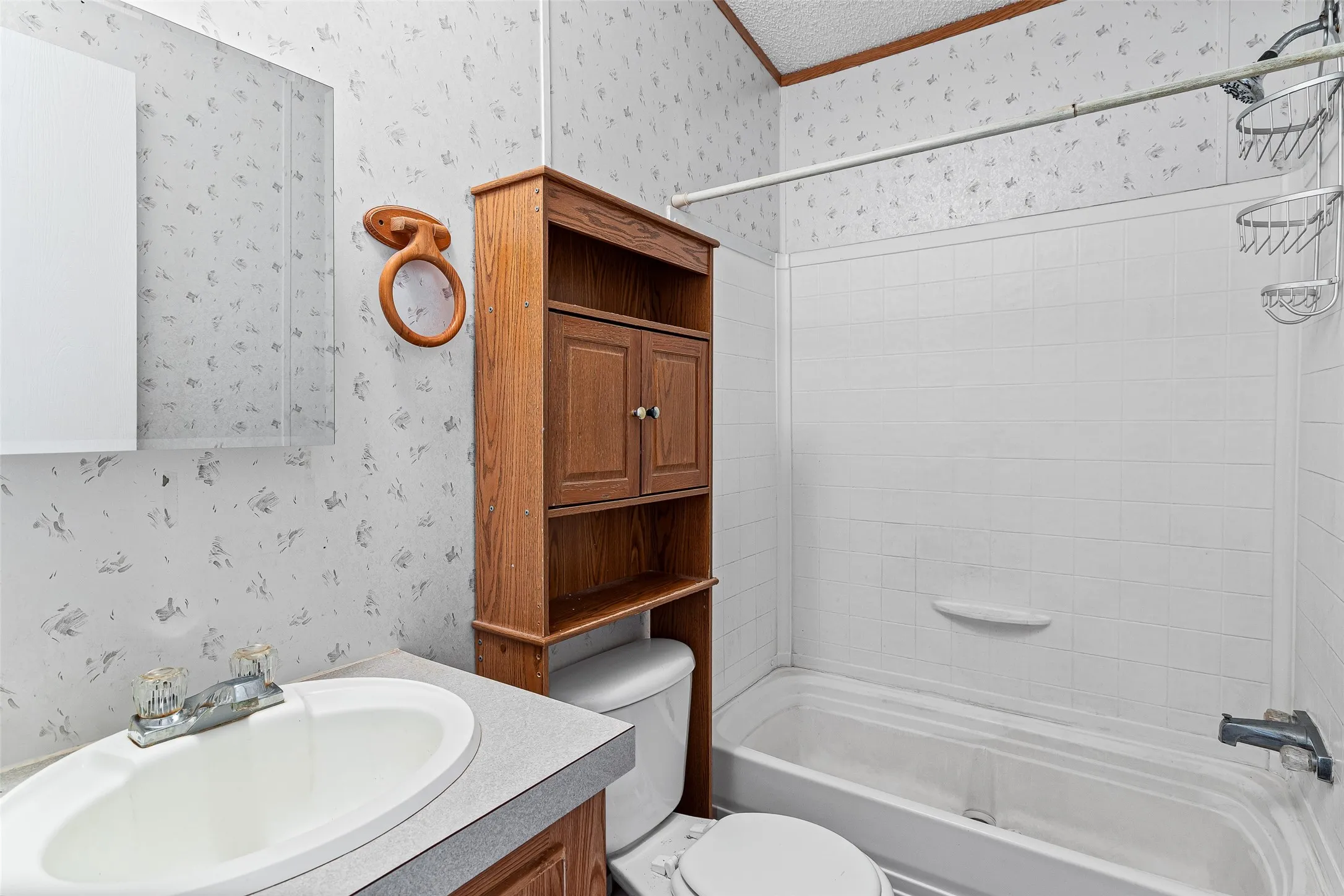 Bathroom featuring a vanity with a laminate countertop, built-in medicine cabinet, and an over-toilet storage unit