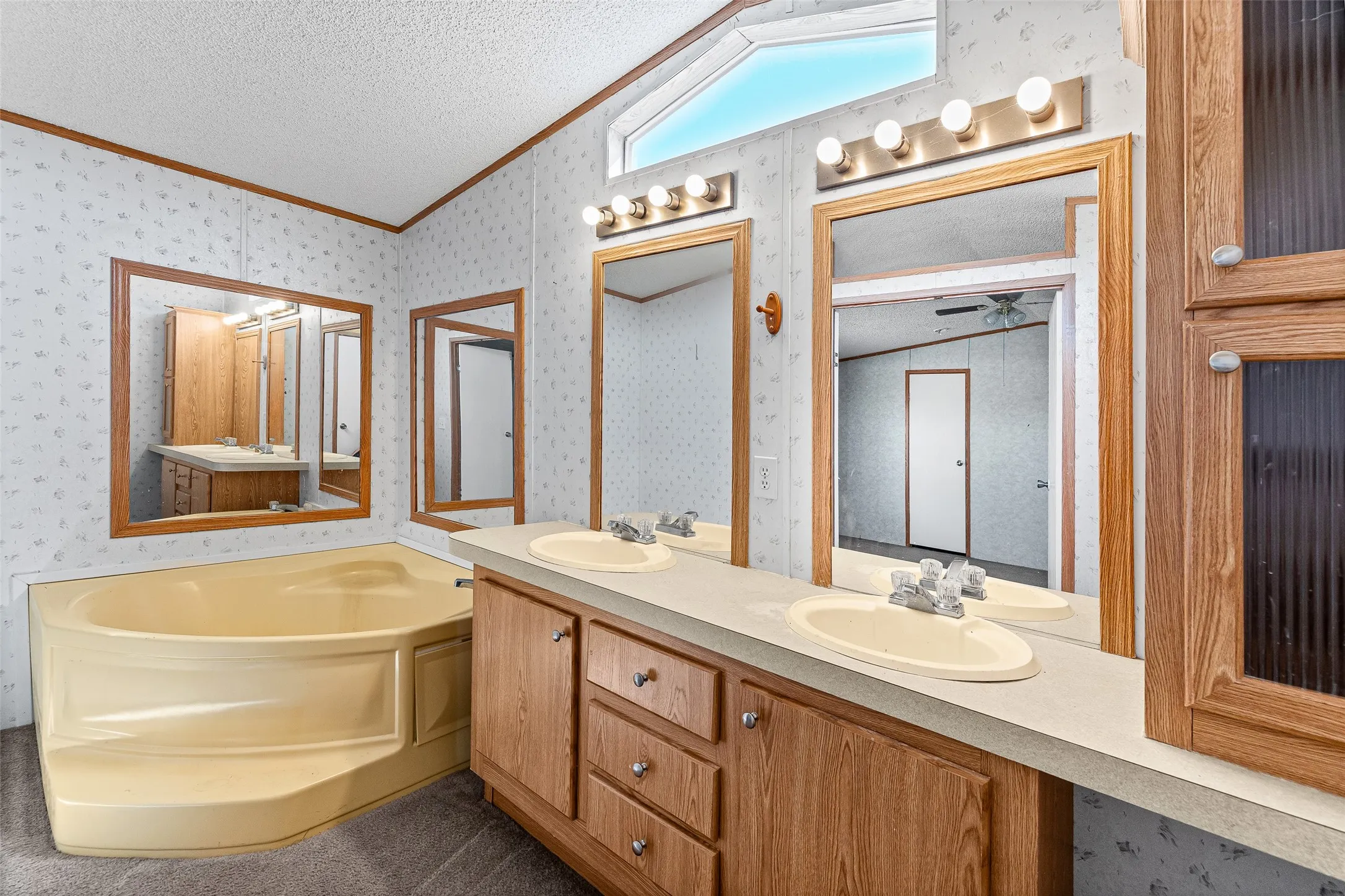 Dual vanity with wood-finish cabinetry, integrated sinks, and individual mirrors