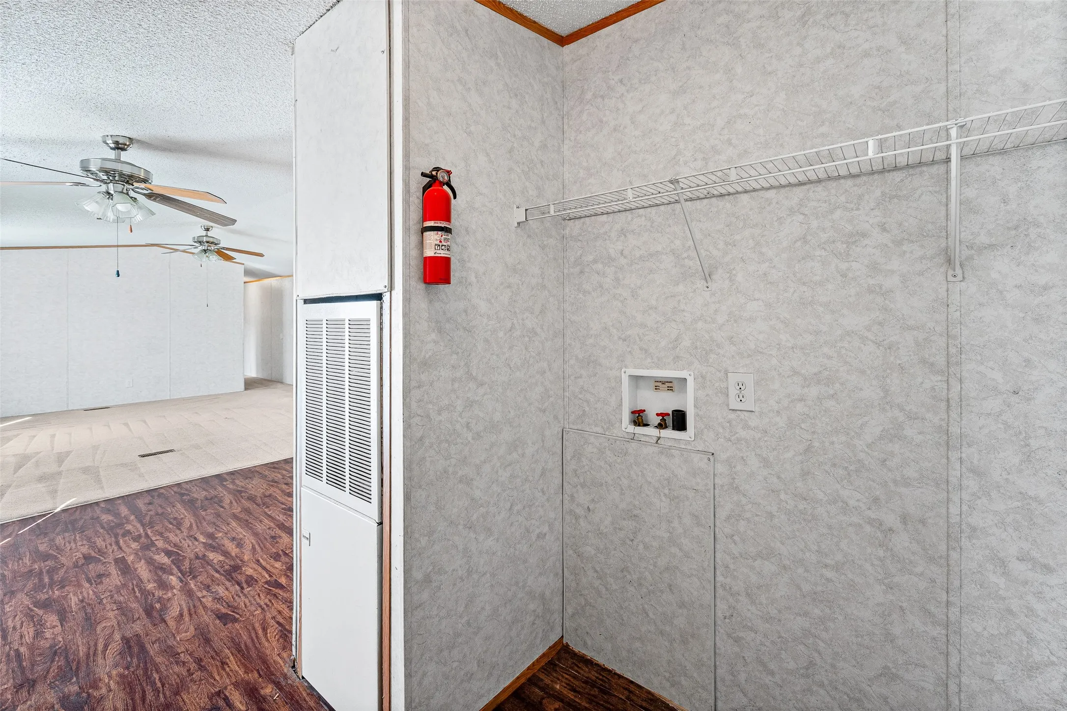 Laundry area with a wire shelf, wall outlet, and utility hookups
