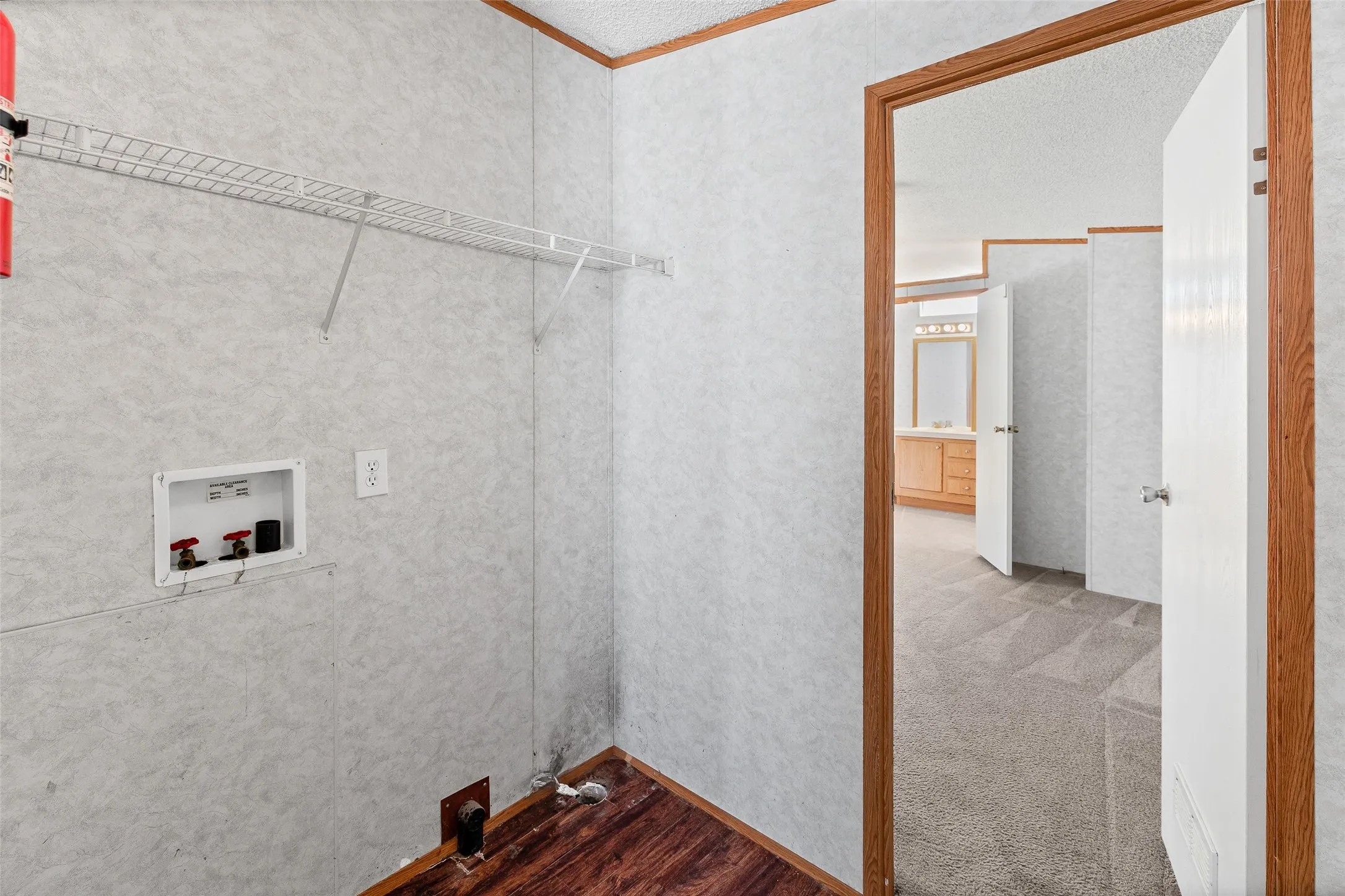 Laundry area with hookups and wire shelving, featuring wood-finish flooring