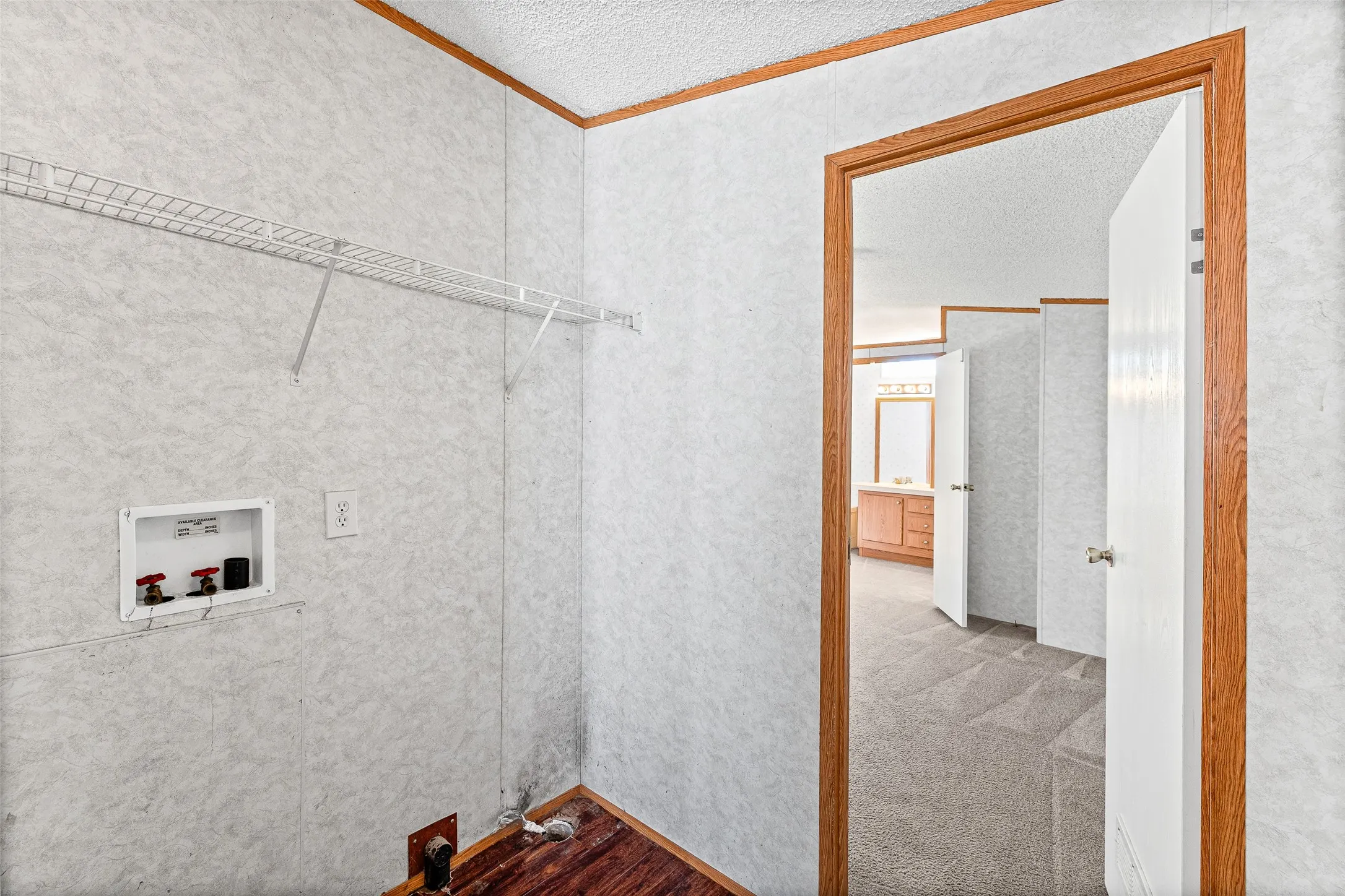 Laundry area featuring a wire shelving unit, wood-finish flooring, and a utility hookup
