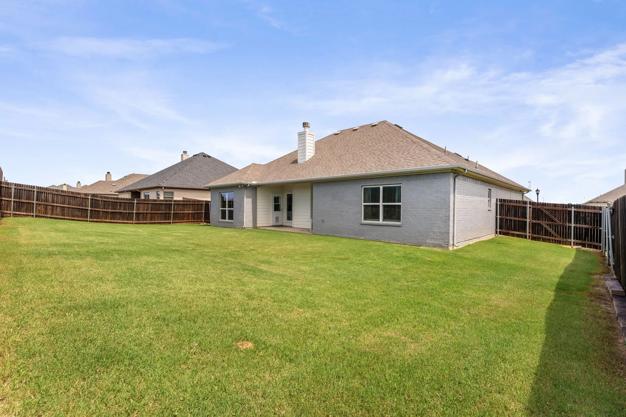 Backyard with freshly stained fencing, large covered back patio.