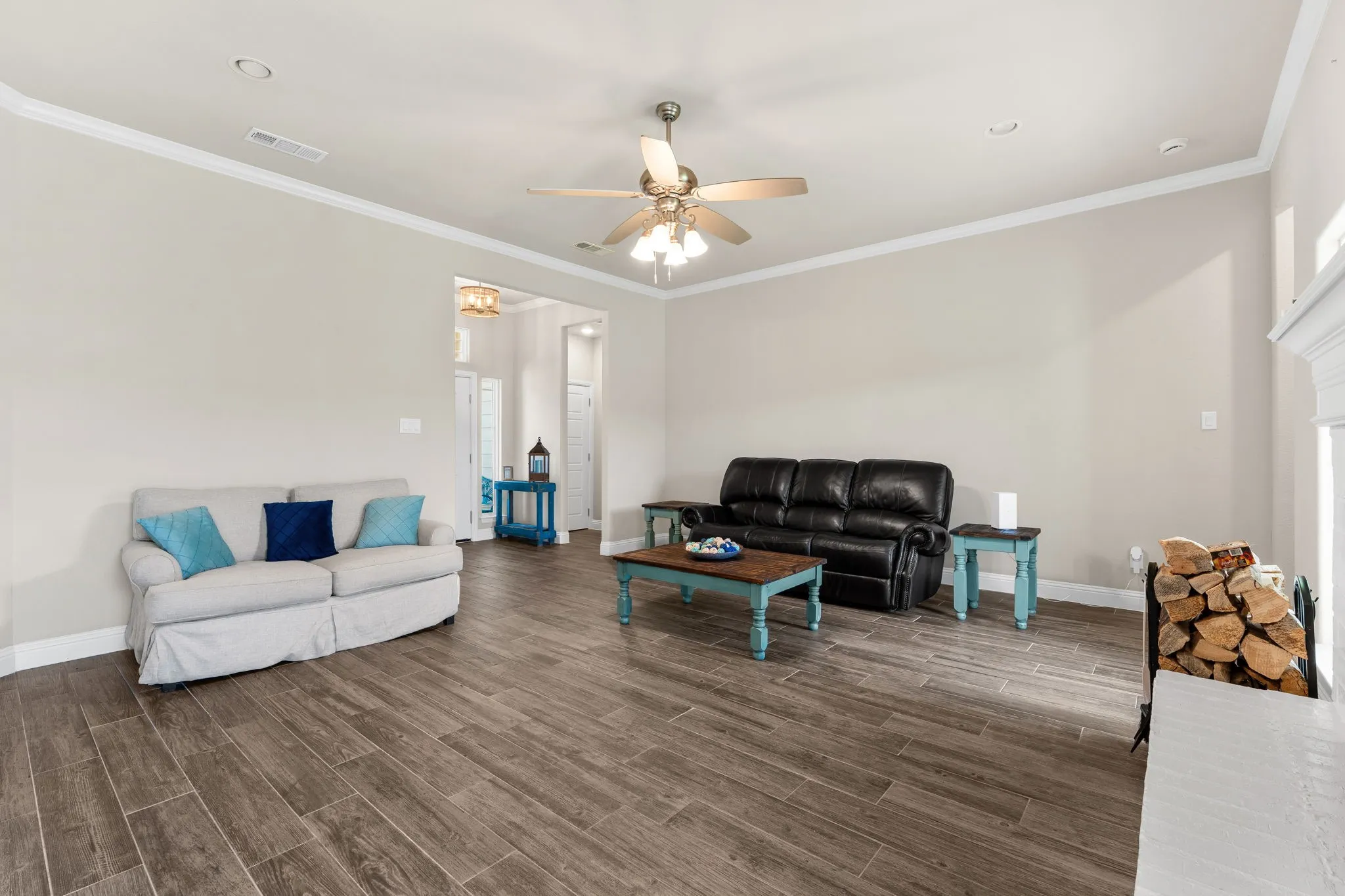 Living Room with ceiling fan, windows for natural lighting, brown/gray wood tile flooring. Crown Moulding.