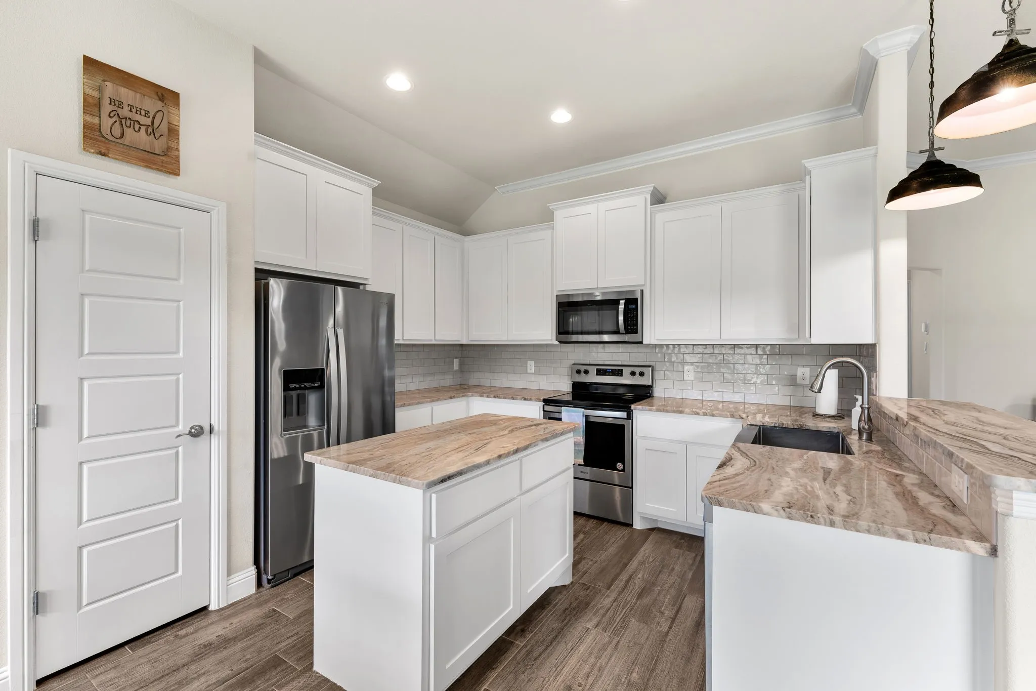 Kitchen with quartz countertops, pantry, stainless steel appliances, decorative lighting above breakfast bar, fresh white painted cabinetry.