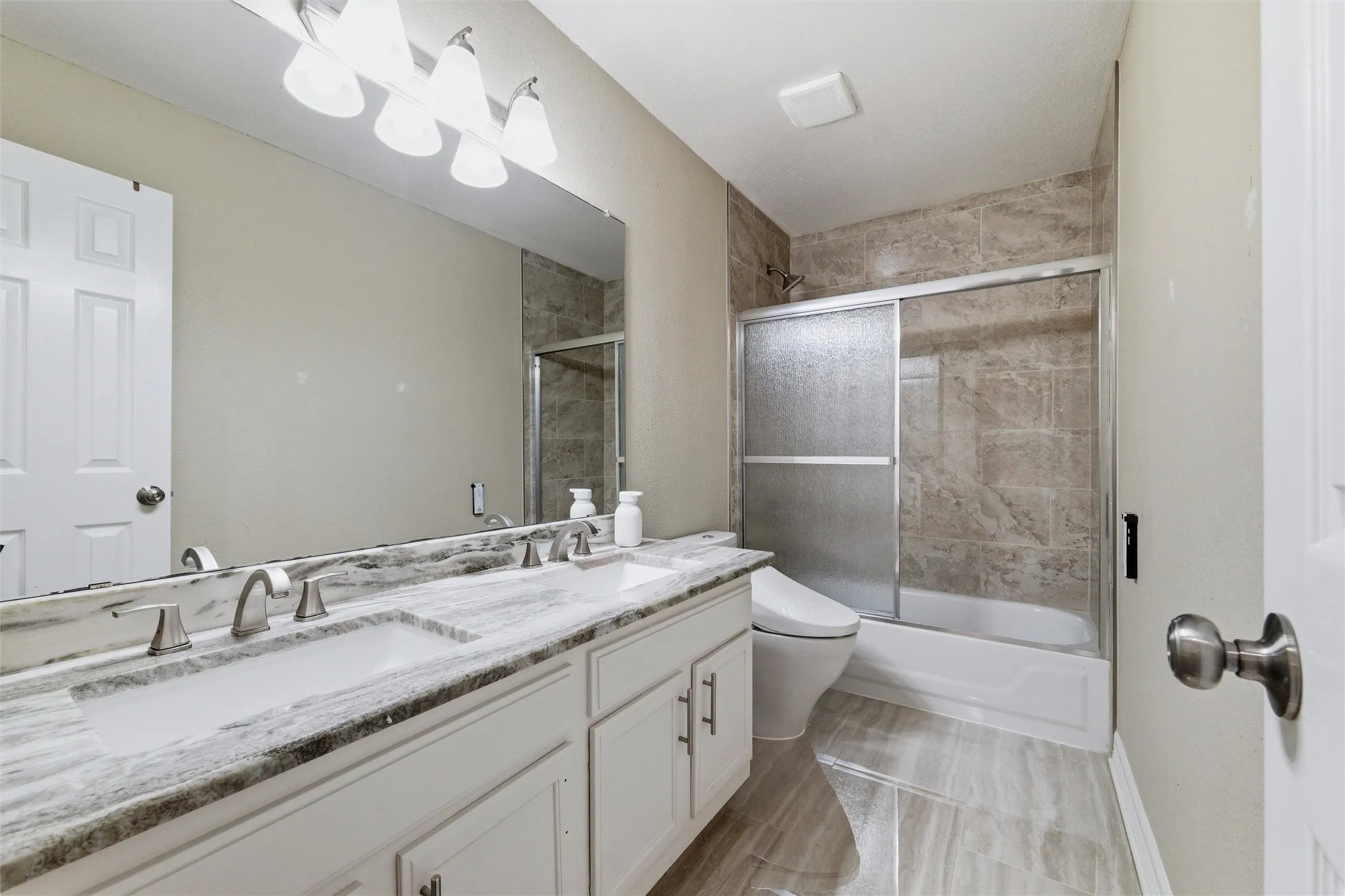 Hall Bath Up with dual sinks, marble counters, floor and tub shower surround with glass enclosure, upgraded bidet commode.