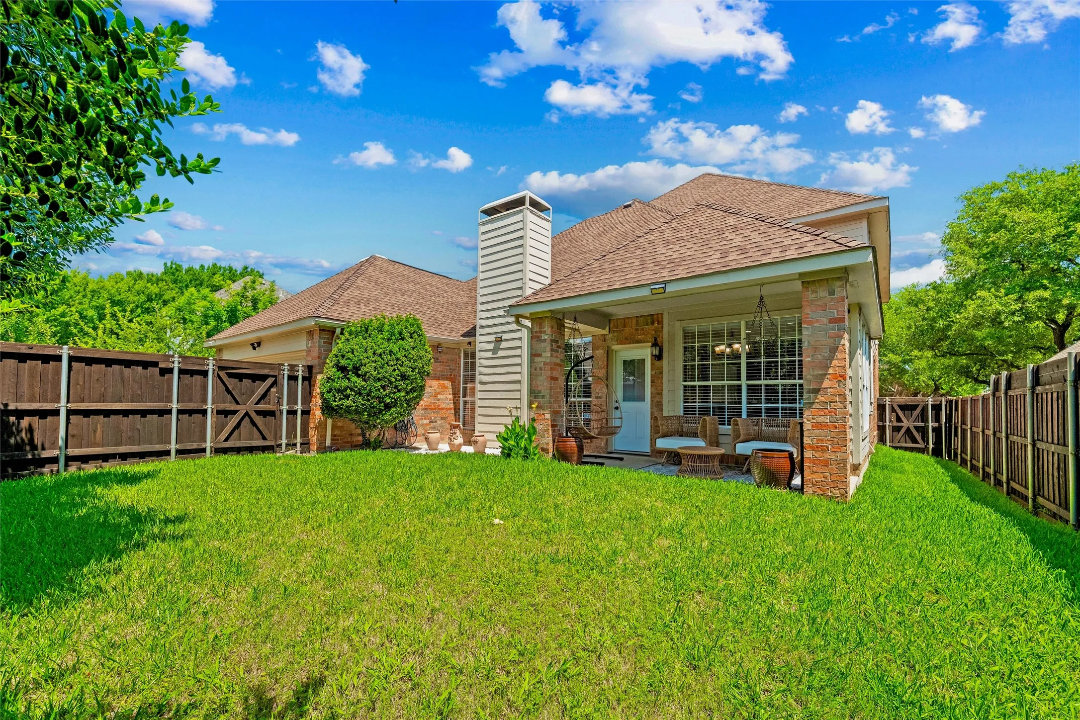 Covered patio, mature landscaping, recently stained board on board fence with steel poles.