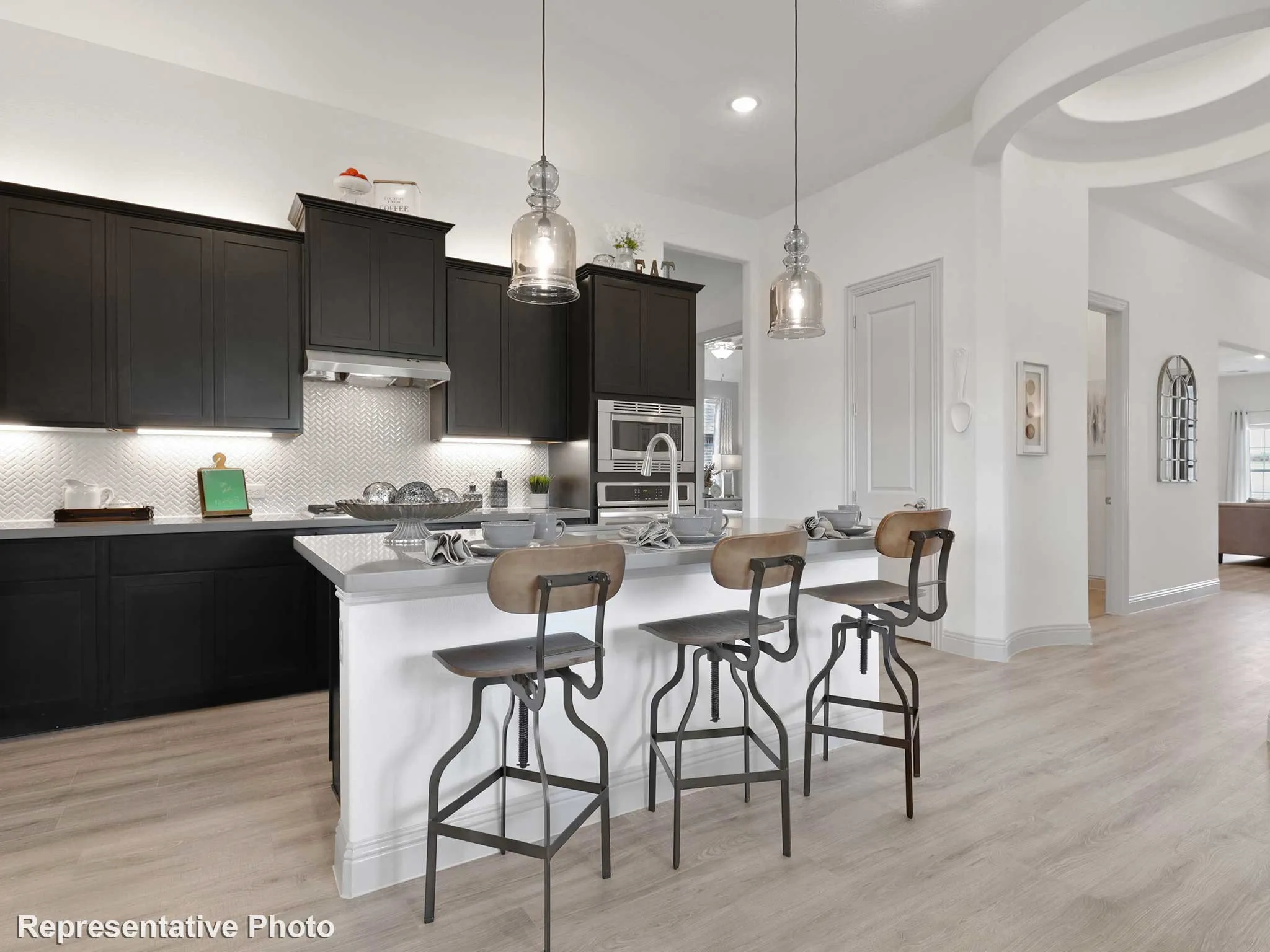 Kitchen island with a light-colored countertop and seating, illuminated by two pendant lights