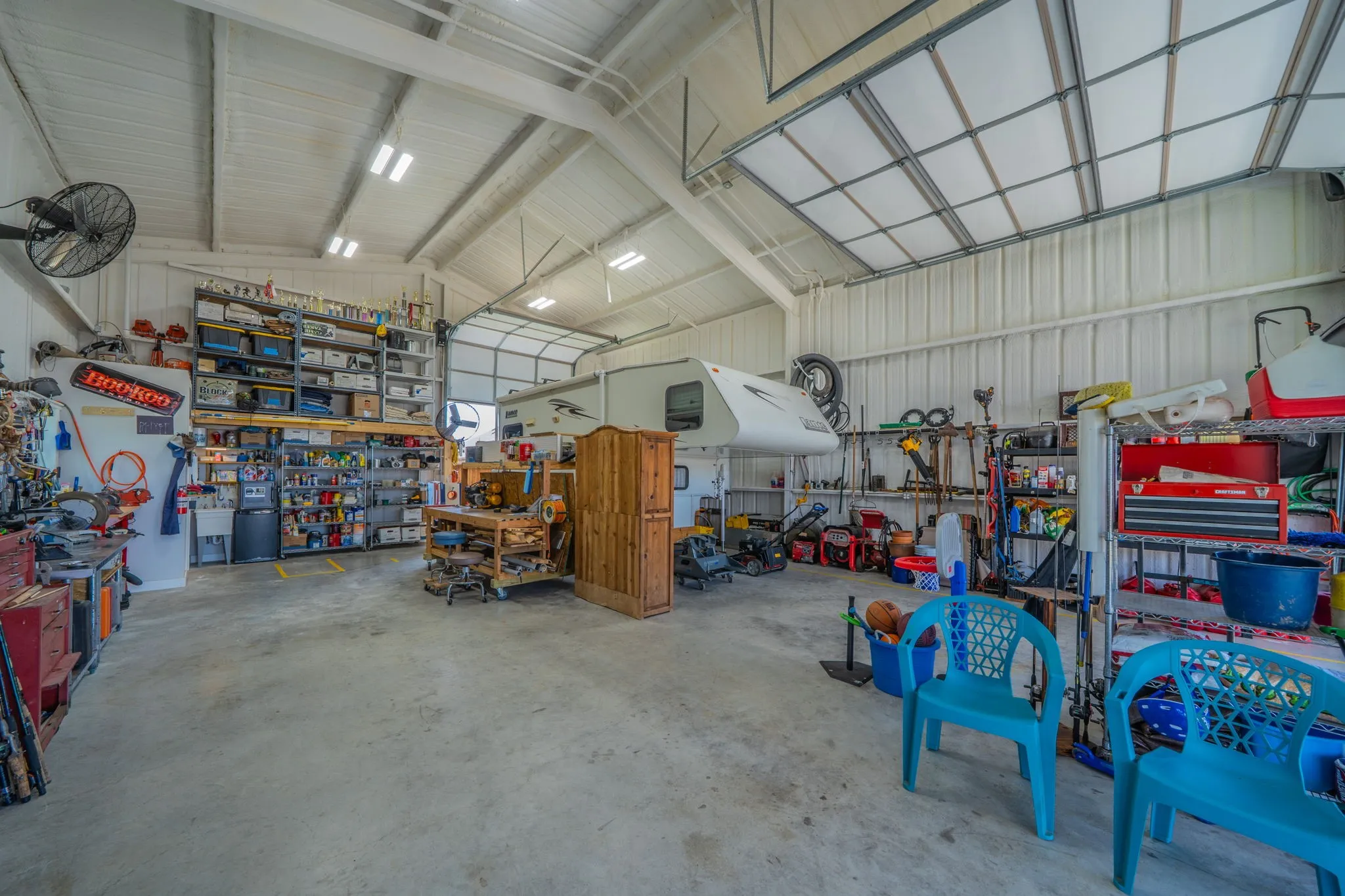 Spacious workshop featuring a 1/2 bathroom, shop sink, 16' high vaulted ceiling, concrete flooring, and multiple High Bay LED light fixtures