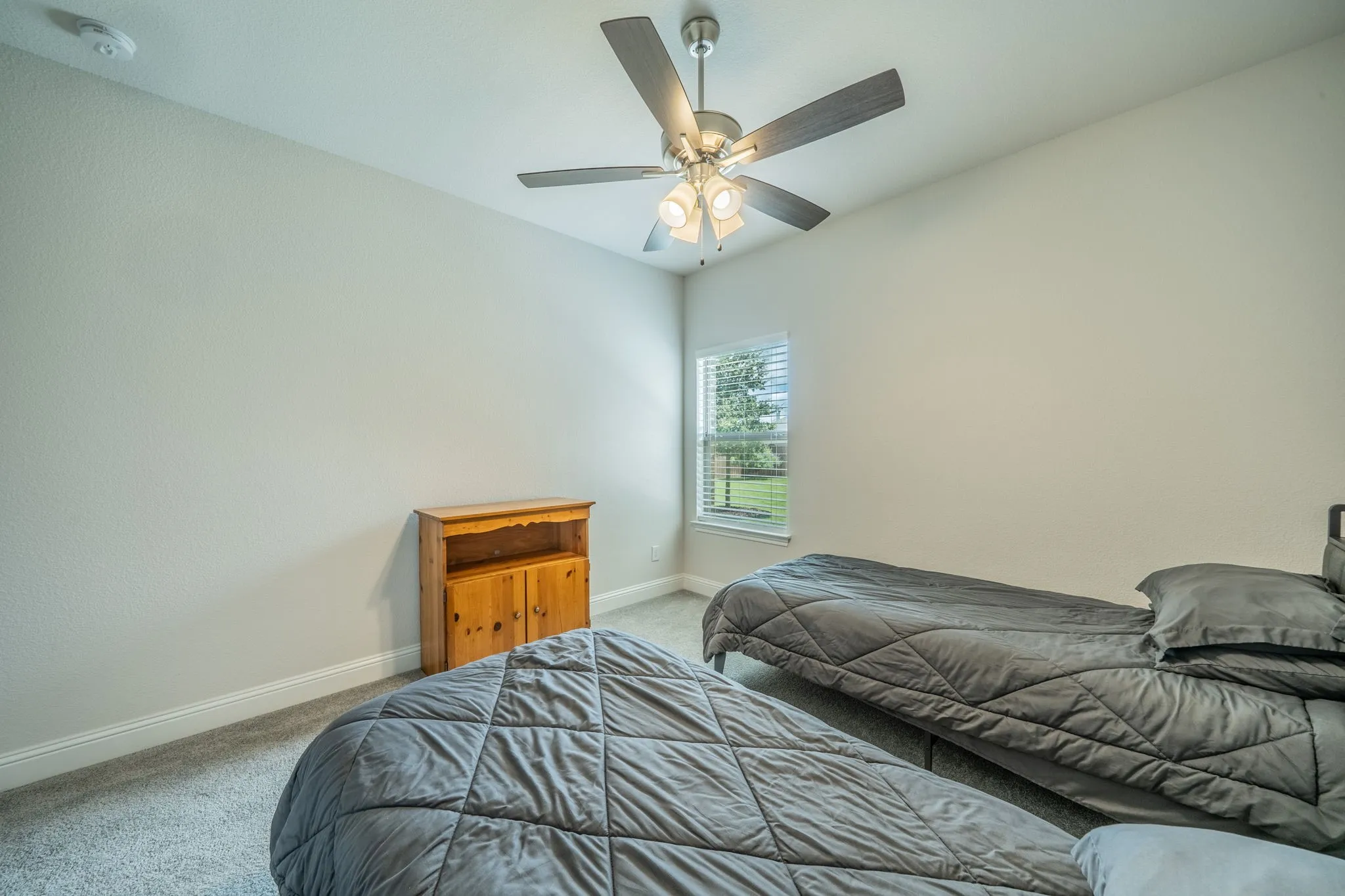Interior room featuring neutral wall paint, light gray carpet, and a ceiling fan with integrated lighting